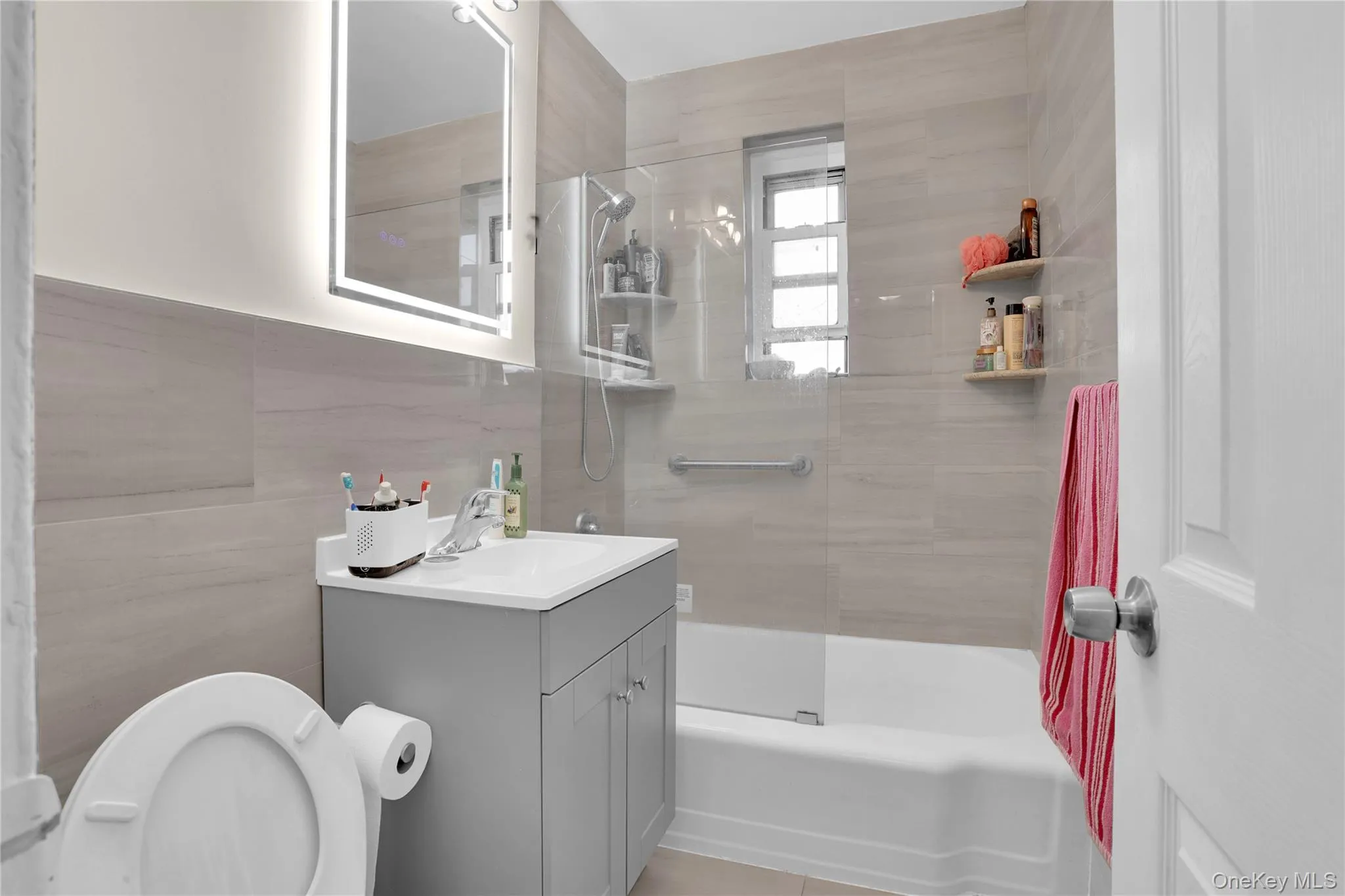 Full bath with vanity, shower / bath combination, and tile walls Full bath with vanity, shower / bath combination, and tile walls