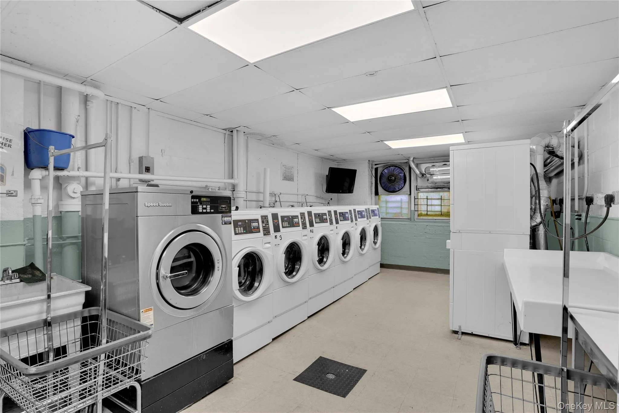 Shared laundry room with independent washer and dryer and a drop ceiling Shared laundry room with independent washer and dryer and a drop ceiling