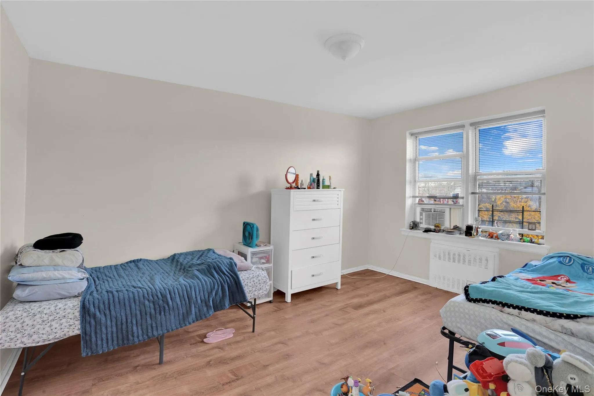 Bedroom featuring radiator heating unit and light wood-style floors Bedroom featuring radiator heating unit and light wood-style floors