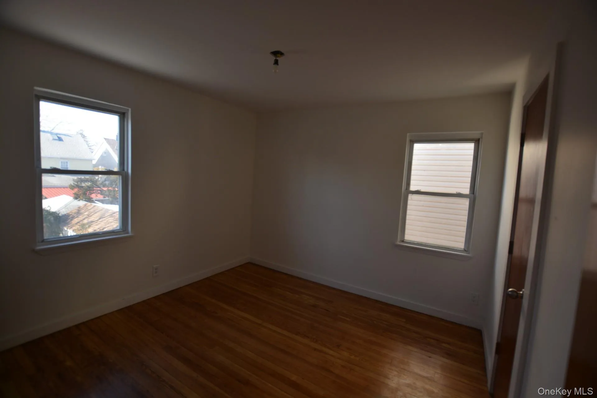 Unfurnished room with dark wood finished floors and plenty of natural light Unfurnished room with dark wood finished floors and plenty of natural light