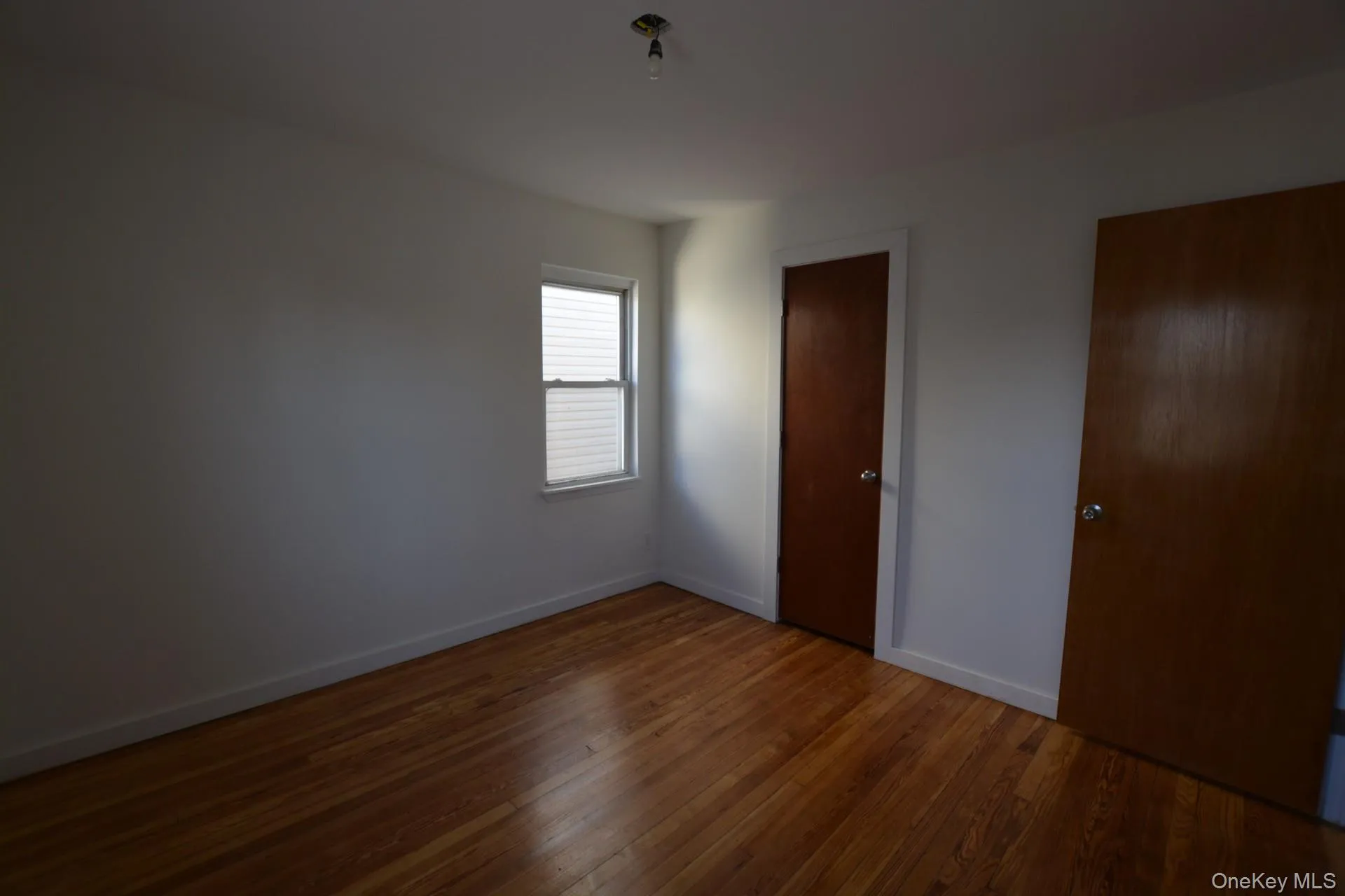 Unfurnished bedroom featuring baseboards and dark wood-style floors Unfurnished bedroom featuring baseboards and dark wood-style floors