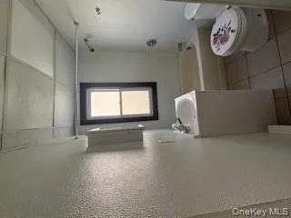 Bathroom featuring vanity, light tile patterned flooring, shower combination, and a textured wall Bathroom featuring vanity, light tile patterned flooring, shower combination, and a textured wall