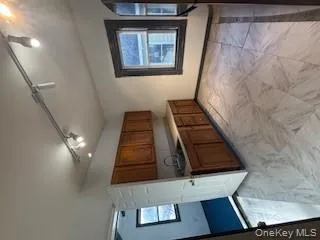 Kitchen featuring brown cabinetry, track lighting, light countertops, light marble finish floors, and fridge Kitchen featuring brown cabinetry, track lighting, light countertops, light marble finish floors, and fridge
