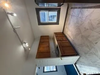 Kitchen featuring brown cabinets, rail lighting, fridge, light countertops, and light marble finish flooring Kitchen featuring brown cabinets, rail lighting, fridge, light countertops, and light marble finish flooring