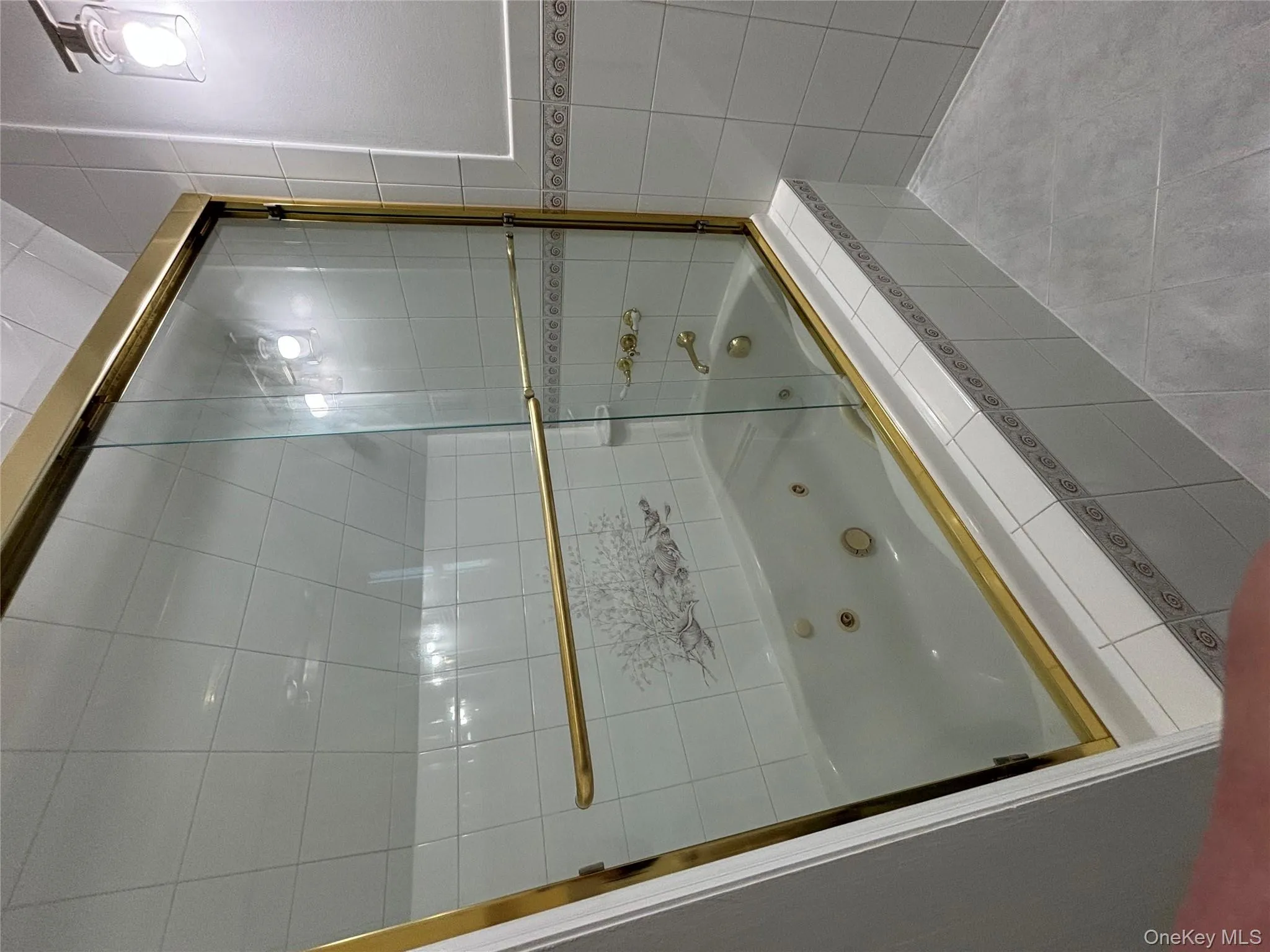 Bathroom featuring tile patterned floors, a combined bath / shower with jetted tub, and tile walls Bathroom featuring tile patterned floors, a combined bath / shower with jetted tub, and tile walls