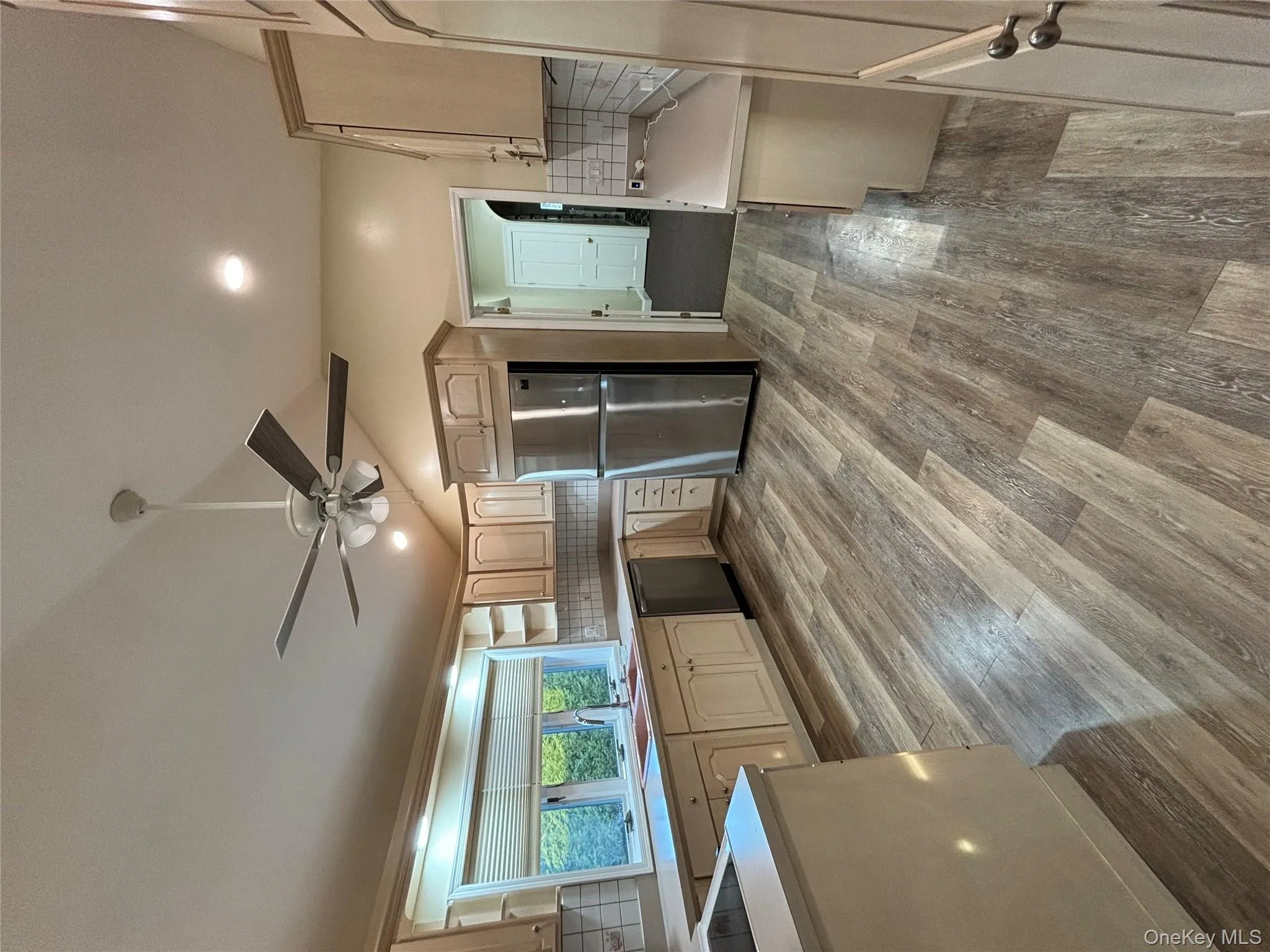 Kitchen with vaulted ceiling, stainless steel refrigerator, light countertops, light brown cabinetry, and dark wood-type flooring Kitchen with vaulted ceiling, stainless steel refrigerator, light countertops, light brown cabinetry, and dark wood-type flooring