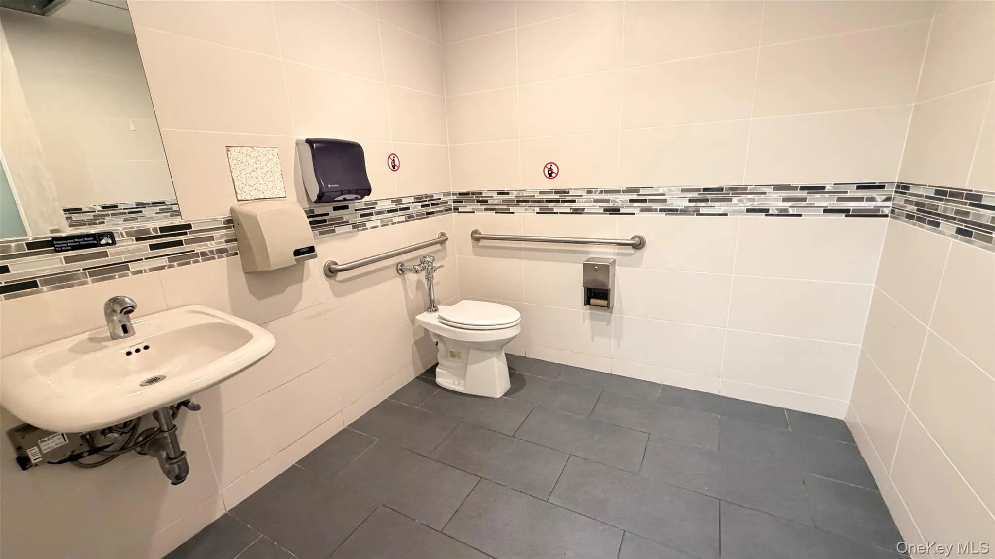 Bathroom with dark tile patterned floors and tile walls Bathroom with dark tile patterned floors and tile walls