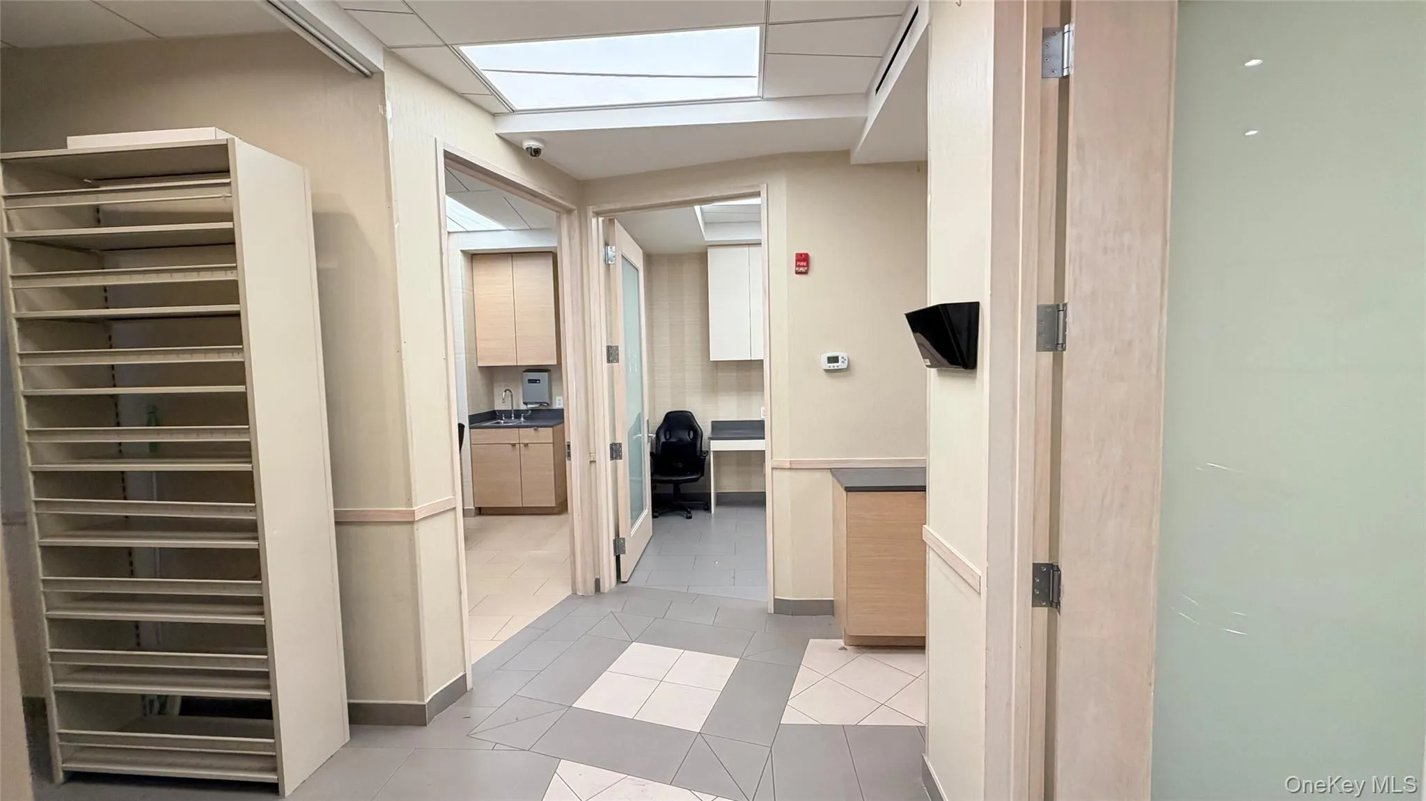 Hallway with a desk, light tile patterned floors, and a skylight Hallway with a desk, light tile patterned floors, and a skylight