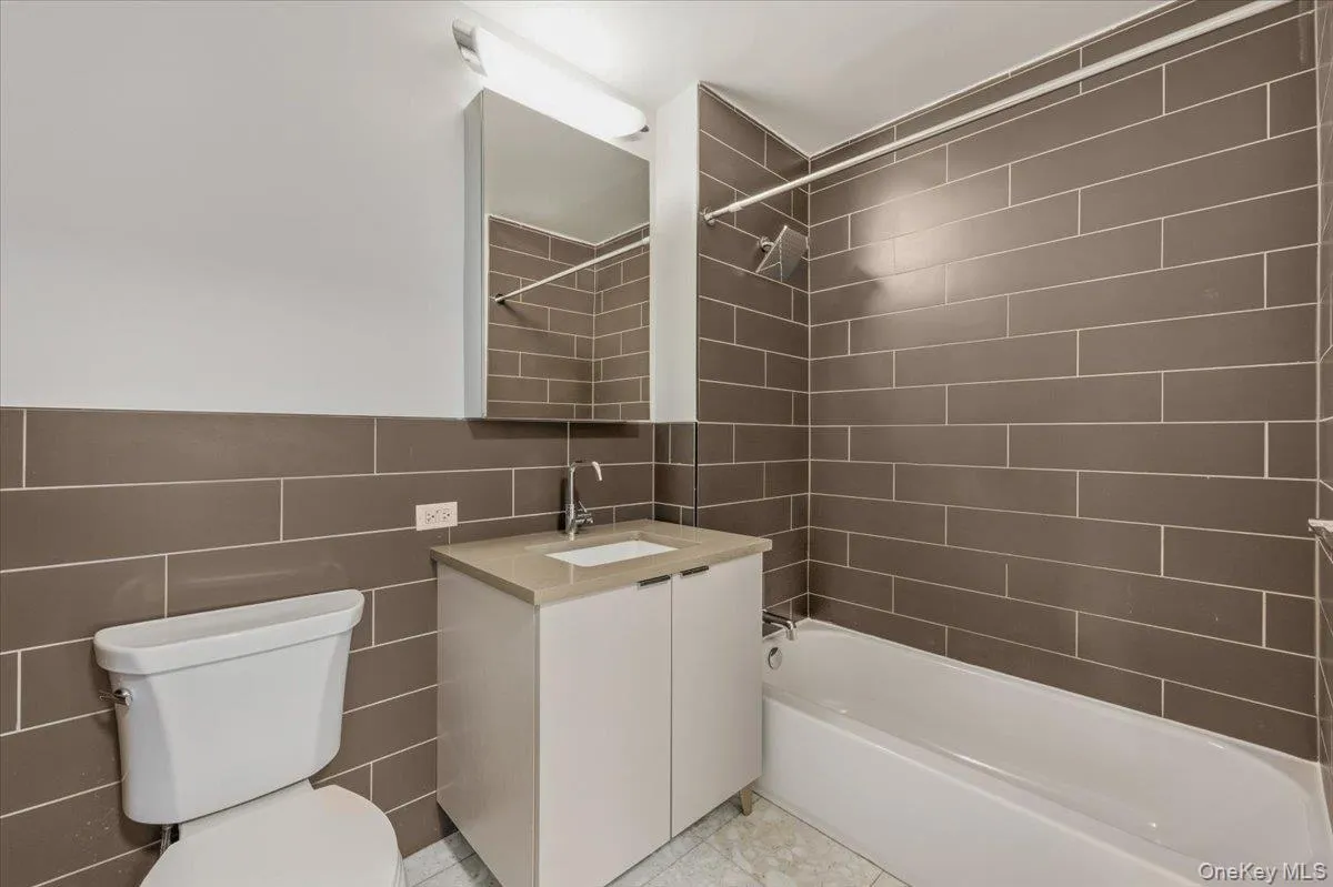 Full bath featuring tile walls, washtub / shower combination, and vanity Full bath featuring tile walls, washtub / shower combination, and vanity