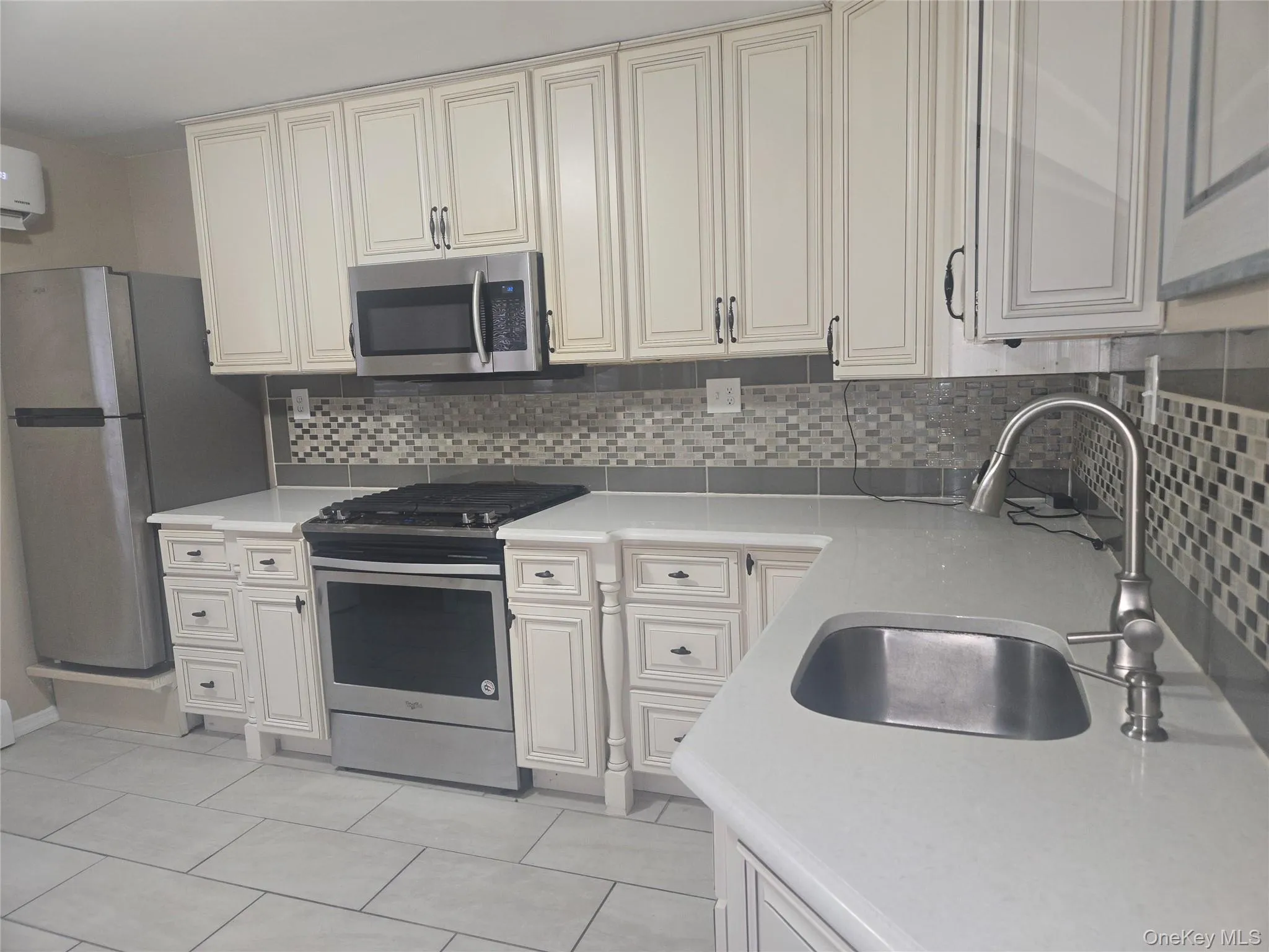 Kitchen featuring stainless steel appliances, light tile patterned floors, tasteful backsplash, and light stone counters Kitchen featuring stainless steel appliances, light tile patterned floors, tasteful backsplash, and light stone counters