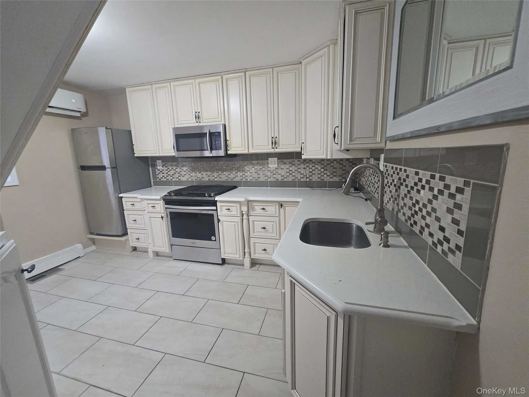 Kitchen with appliances with stainless steel finishes, tasteful backsplash, light stone countertops, a wall unit AC, and light tile patterned floors Kitchen with appliances with stainless steel finishes, tasteful backsplash, light stone countertops, a wall unit AC, and light tile patterned floors