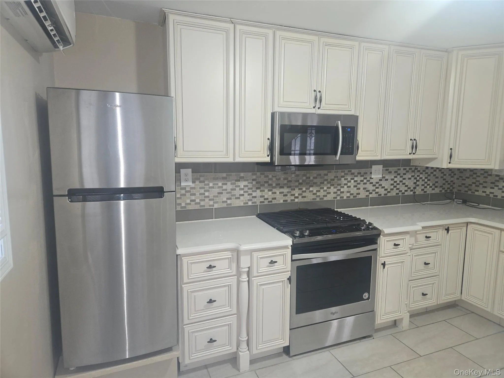 Kitchen with stainless steel appliances, tasteful backsplash, light stone countertops, and white cabinets Kitchen with stainless steel appliances, tasteful backsplash, light stone countertops, and white cabinets