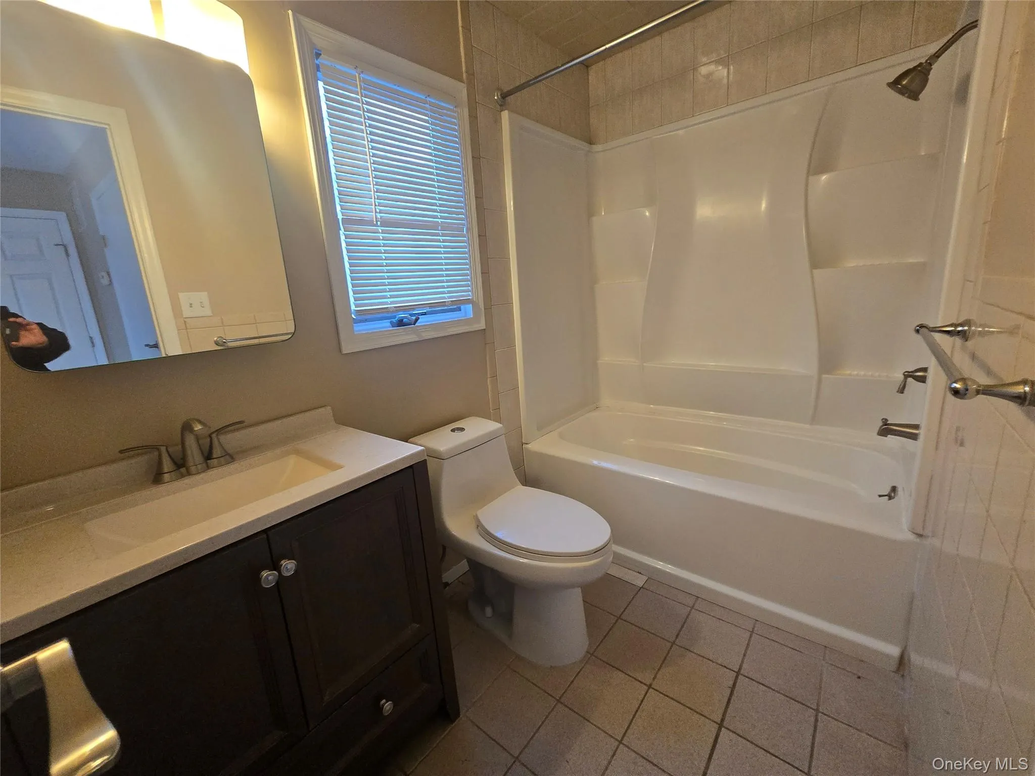 Full bath with light tile patterned floors, vanity, and washtub / shower combination Full bath with light tile patterned floors, vanity, and washtub / shower combination
