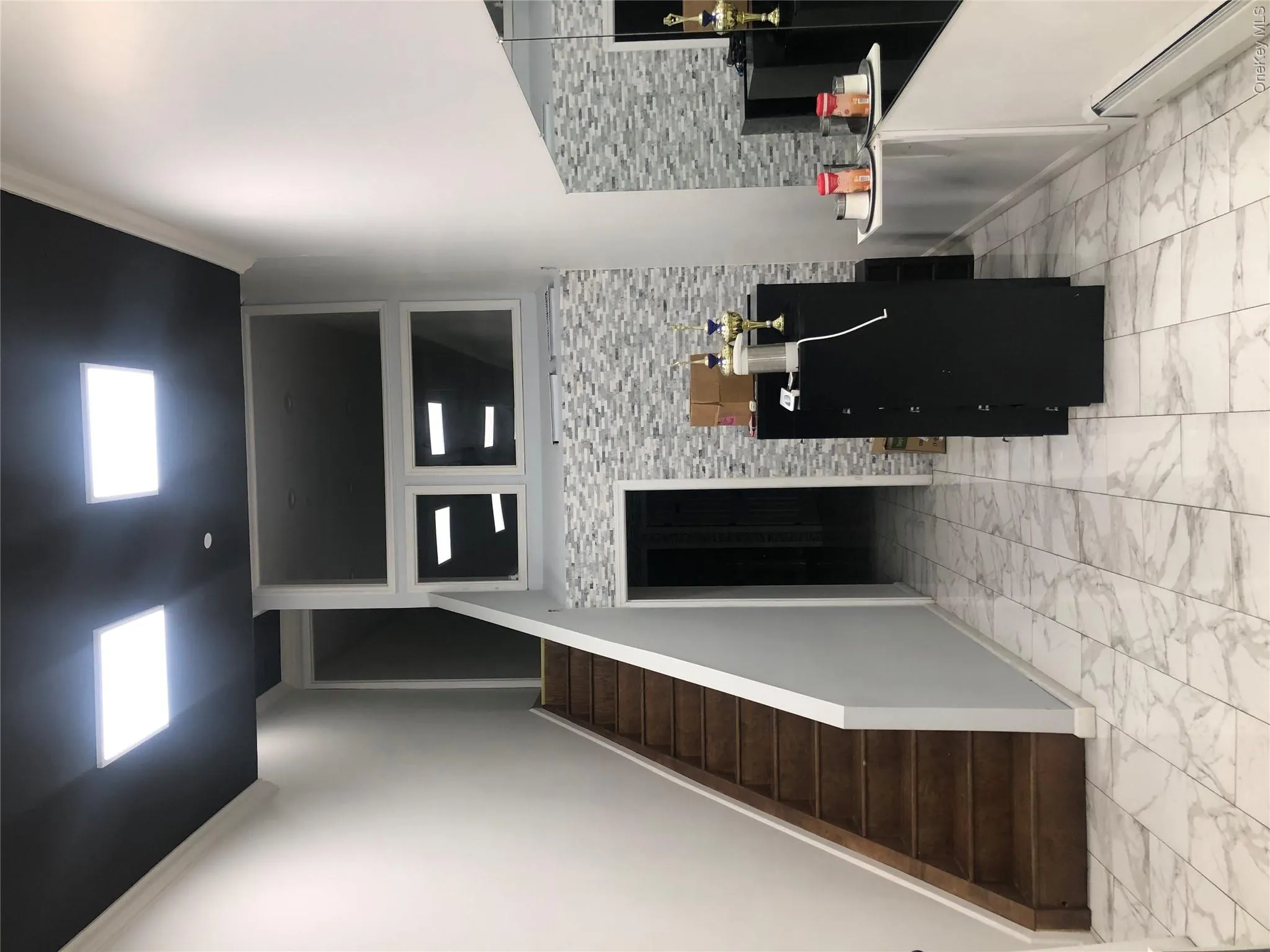 Kitchen featuring a baseboard heating unit, light marble finish floors, ornamental molding, and dark cabinets Kitchen featuring a baseboard heating unit, light marble finish floors, ornamental molding, and dark cabinets