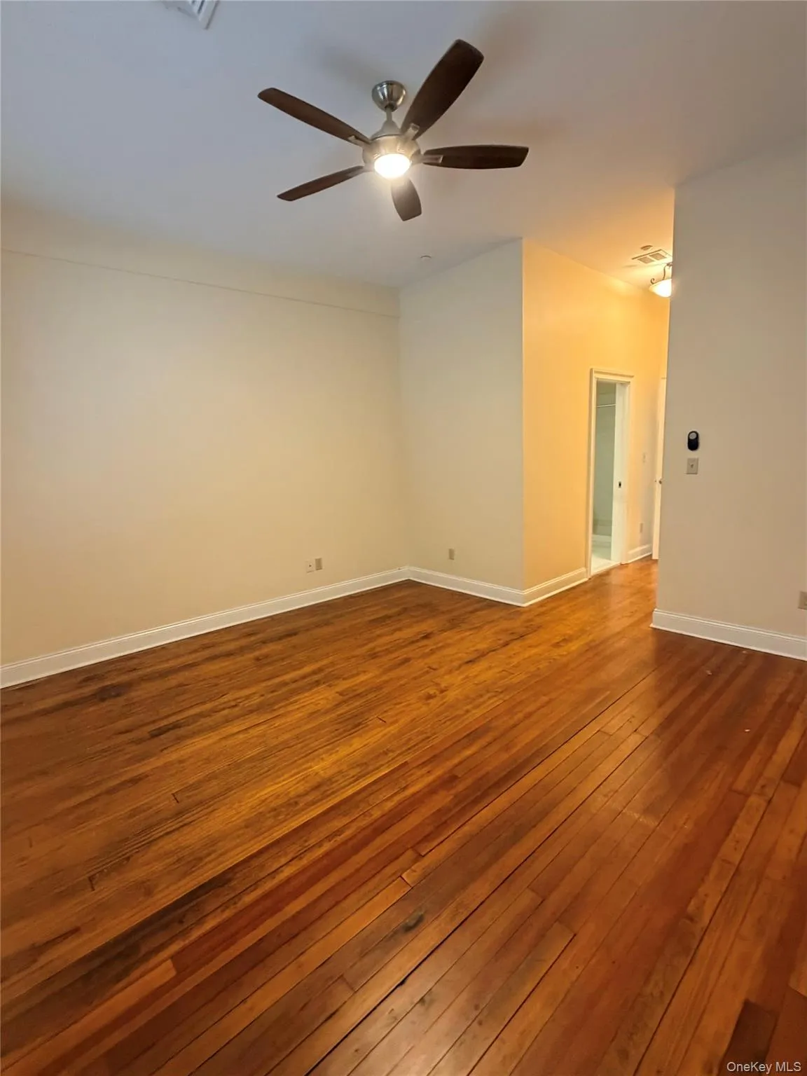 Empty room with dark wood-type flooring and a ceiling fan Empty room with dark wood-type flooring and a ceiling fan