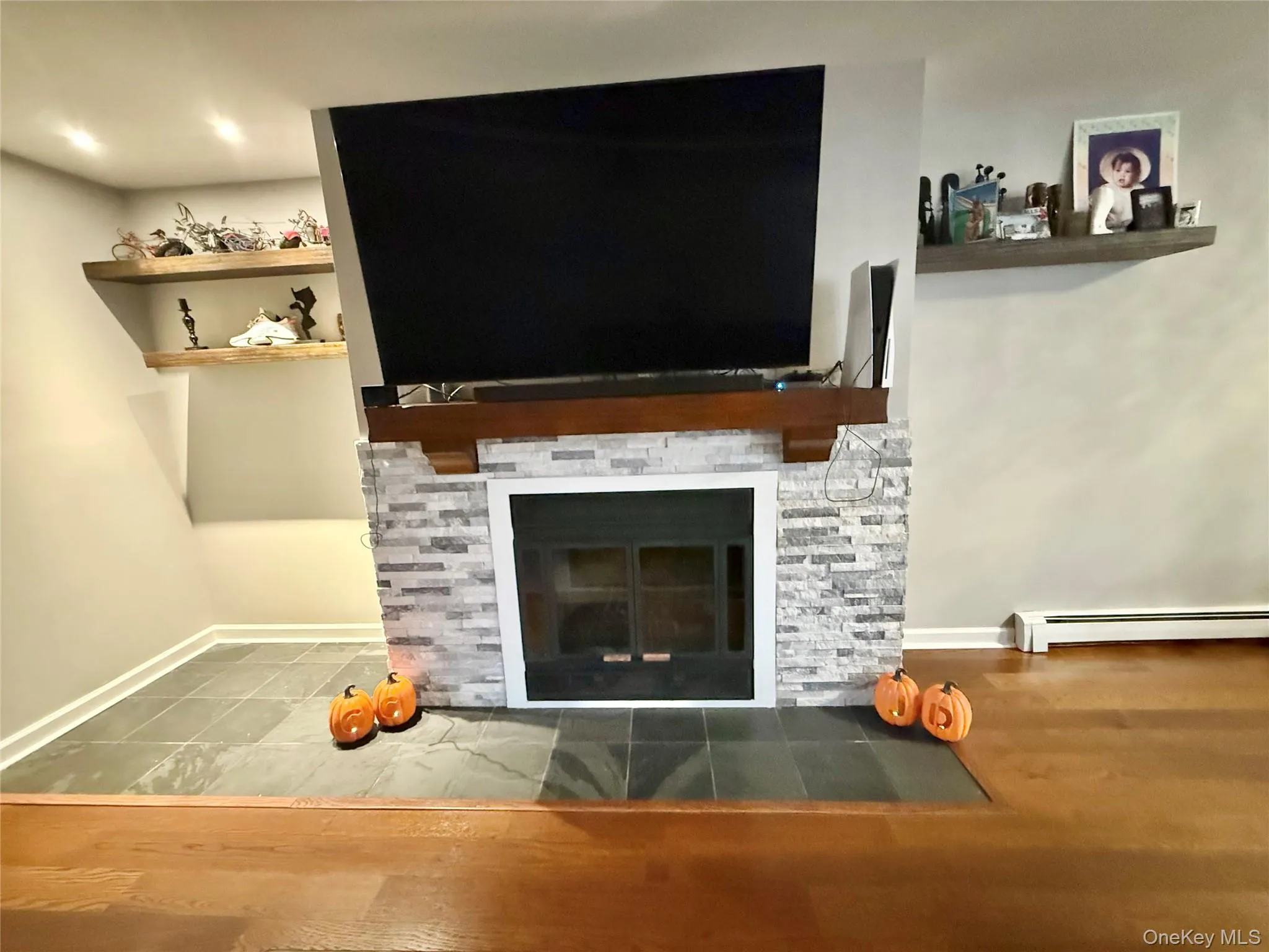 Detailed view of wood finished floors, a baseboard radiator, and a fireplace Detailed view of wood finished floors, a baseboard radiator, and a fireplace