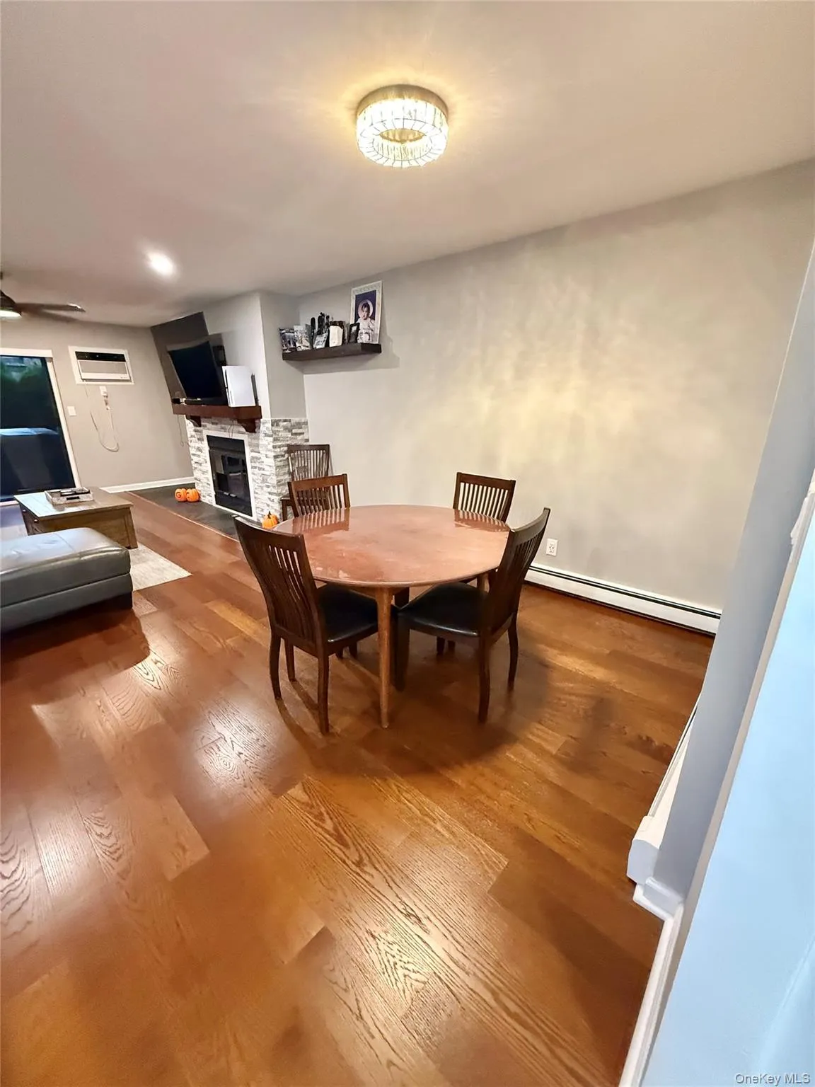 Dining area featuring a fireplace, dark wood-style floors, and a baseboard heating unit Dining area featuring a fireplace, dark wood-style floors, and a baseboard heating unit