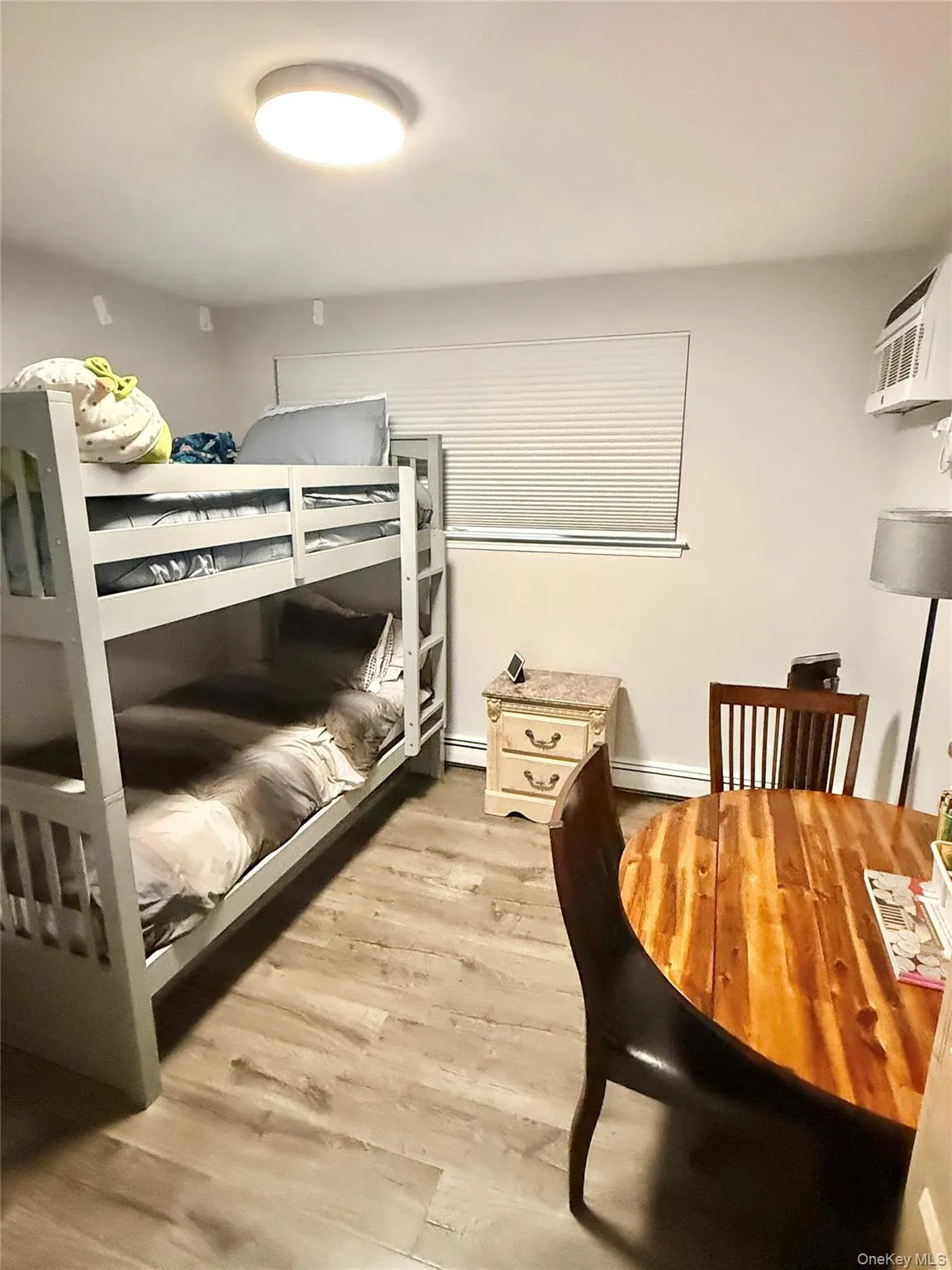 Bedroom featuring light wood-style flooring and a wall unit AC Bedroom featuring light wood-style flooring and a wall unit AC