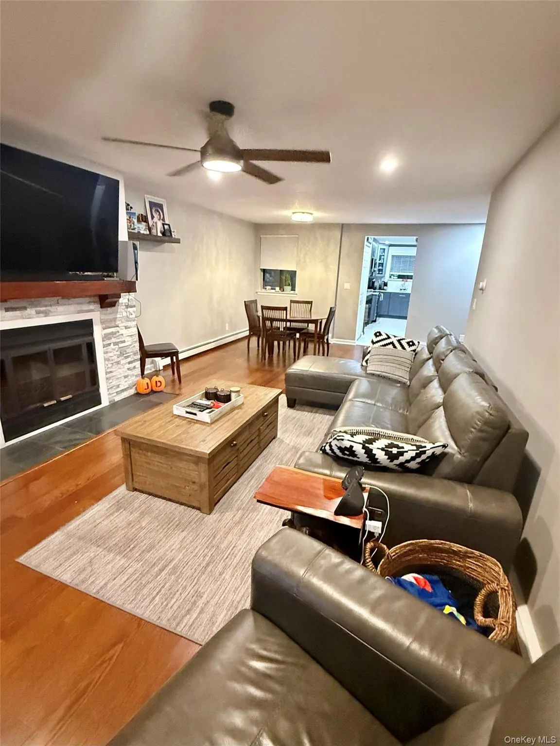 Living room featuring a fireplace, wood finished floors, and ceiling fan Living room featuring a fireplace, wood finished floors, and ceiling fan