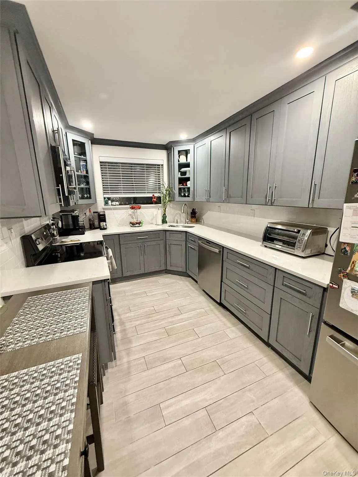 Kitchen with decorative backsplash, gray cabinetry, light stone counters, appliances with stainless steel finishes, and recessed lighting Kitchen with decorative backsplash, gray cabinetry, light stone counters, appliances with stainless steel finishes, and recessed lighting