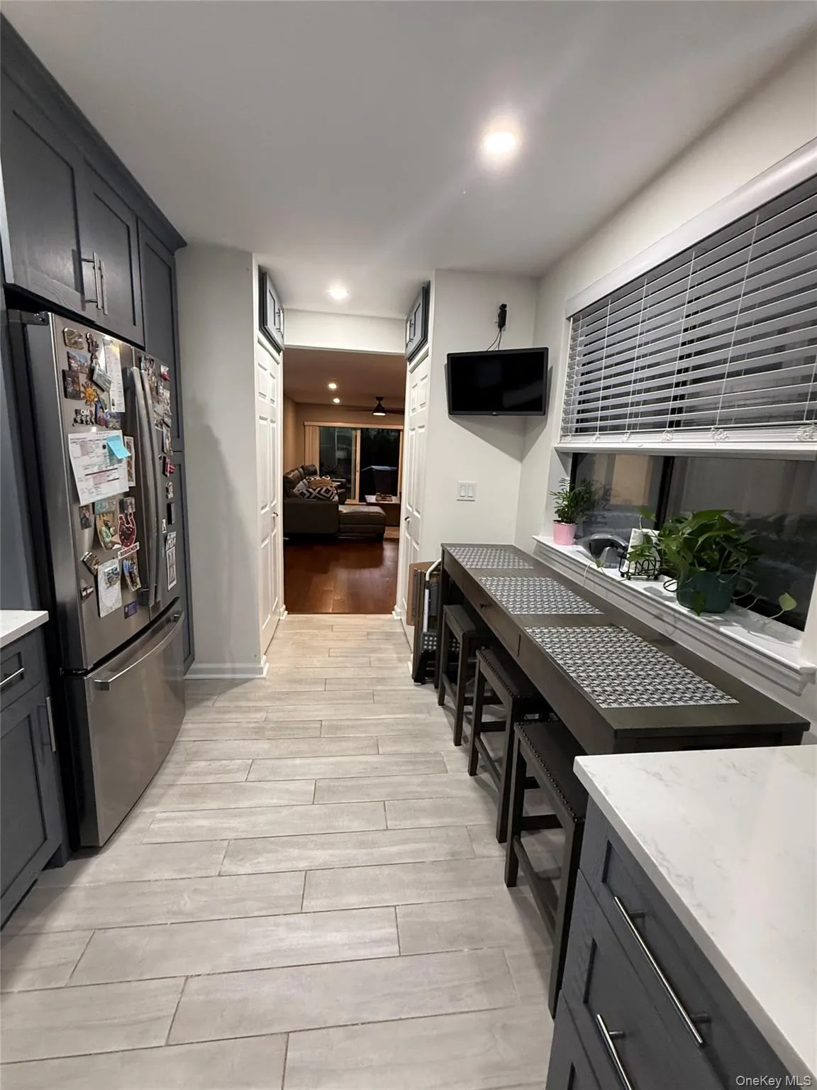 Kitchen featuring freestanding refrigerator, light stone counters, light wood-style floors, gray cabinets, and recessed lighting Kitchen featuring freestanding refrigerator, light stone counters, light wood-style floors, gray cabinets, and recessed lighting