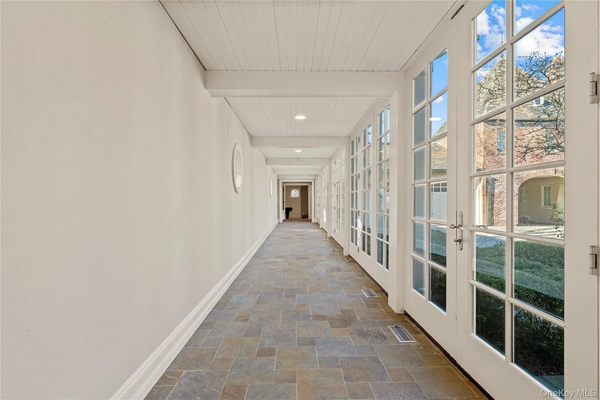 Corridor with stone finish floors, beamed ceiling, and french doors Corridor with stone finish floors, beamed ceiling, and french doors