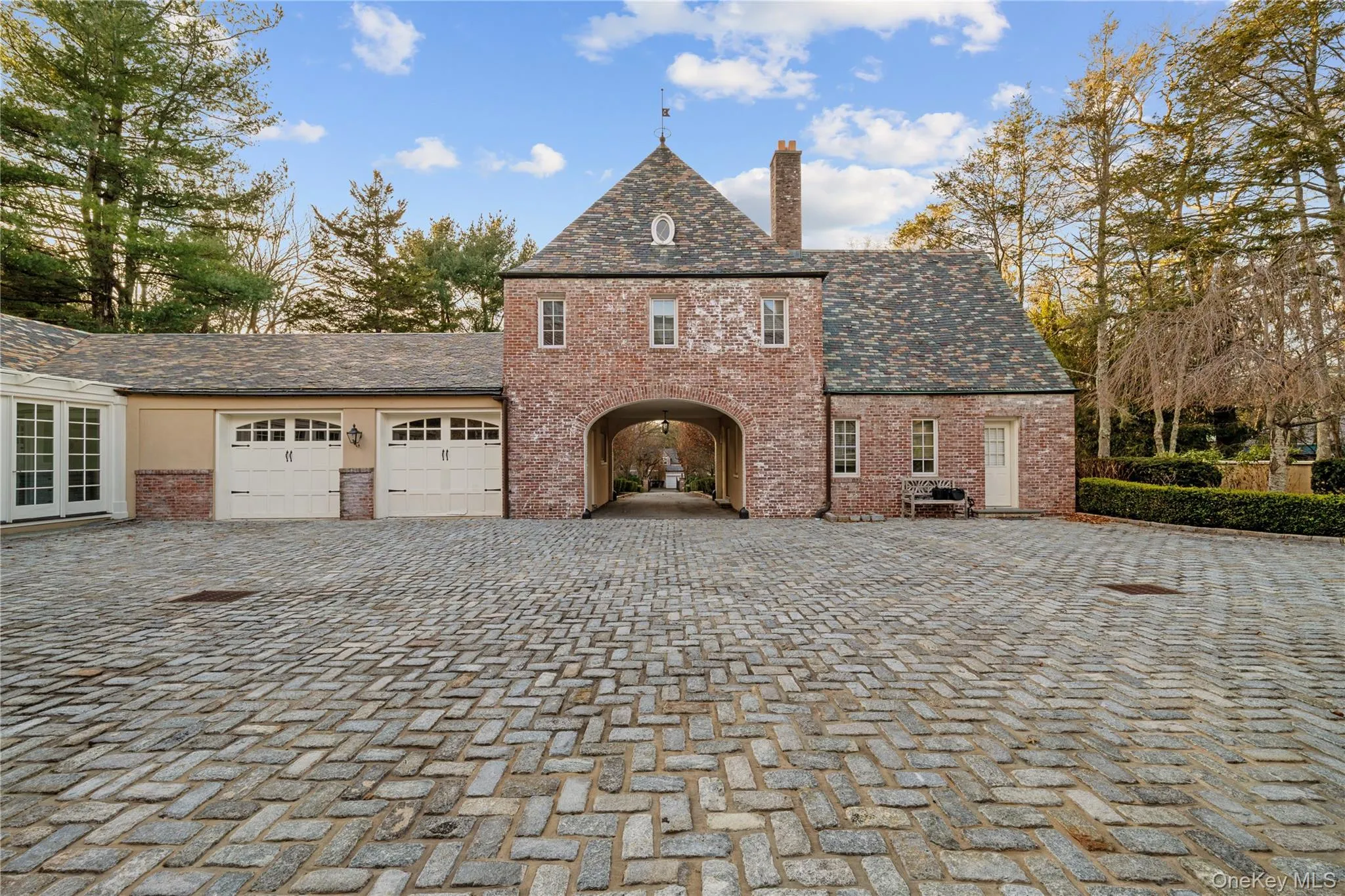 View of home's exterior with brick siding, a garage, a chimney, and decorative driveway View of home's exterior with brick siding, a garage, a chimney, and decorative driveway