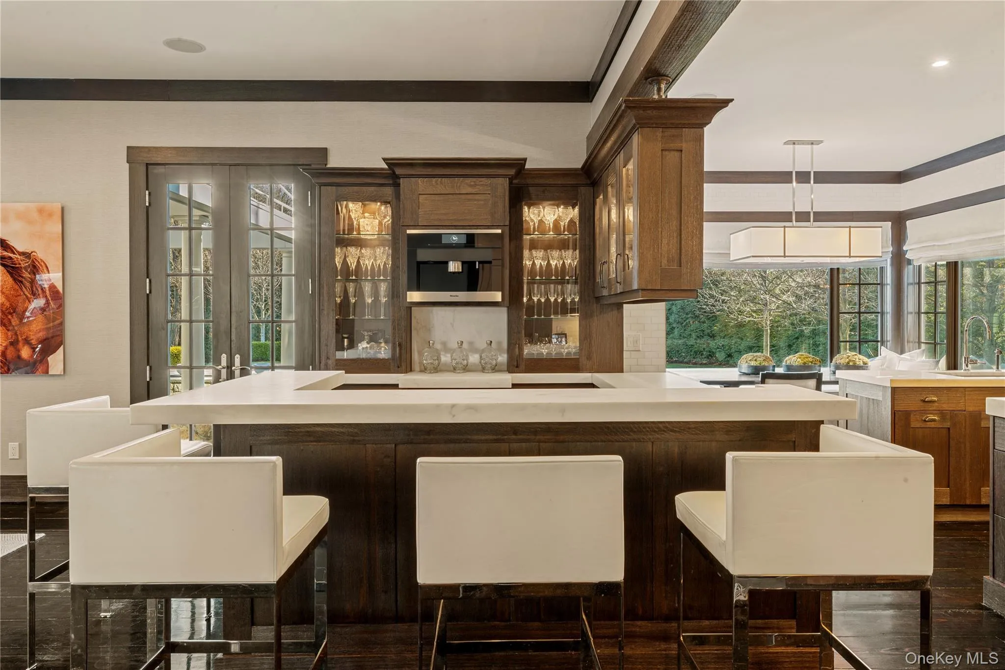 Indoor bar with light countertops, decorative backsplash, glass insert cabinets, pendant lighting, and stainless steel microwave Indoor bar with light countertops, decorative backsplash, glass insert cabinets, pendant lighting, and stainless steel microwave