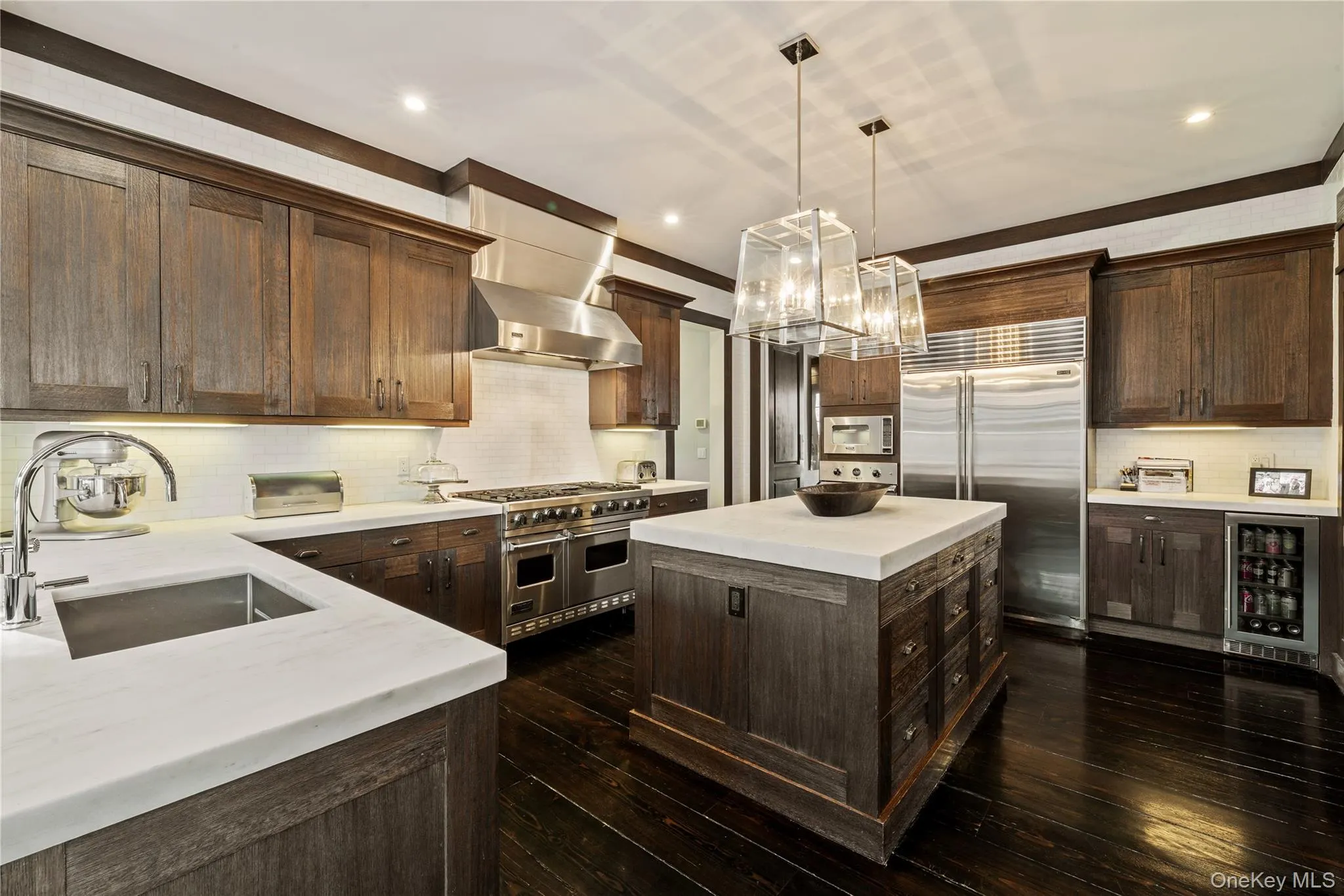 Kitchen featuring hanging light fixtures, high quality appliances, dark brown cabinets, wine cooler, and a kitchen island Kitchen featuring hanging light fixtures, high quality appliances, dark brown cabinets, wine cooler, and a kitchen island