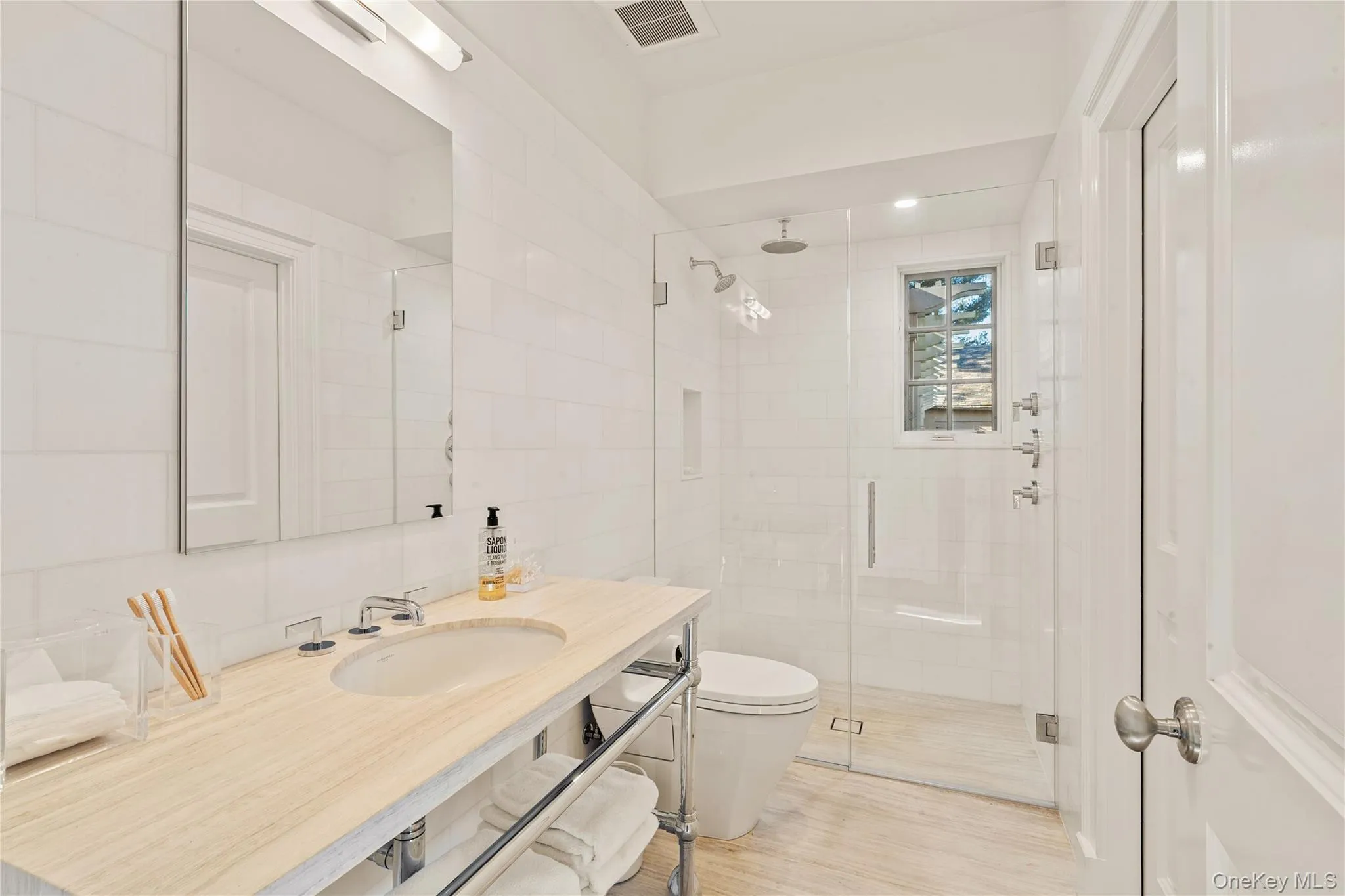 Full bath featuring a shower stall, vanity, light wood-type flooring, and tile walls Full bath featuring a shower stall, vanity, light wood-type flooring, and tile walls