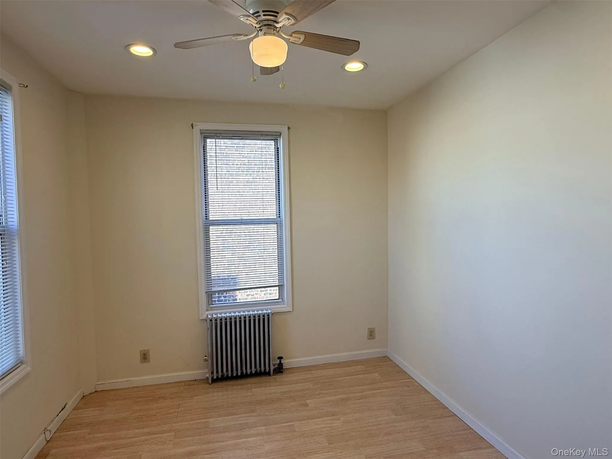 Spare room featuring radiator heating unit, light wood-style flooring, a ceiling fan, and recessed lighting Spare room featuring radiator heating unit, light wood-style flooring, a ceiling fan, and recessed lighting