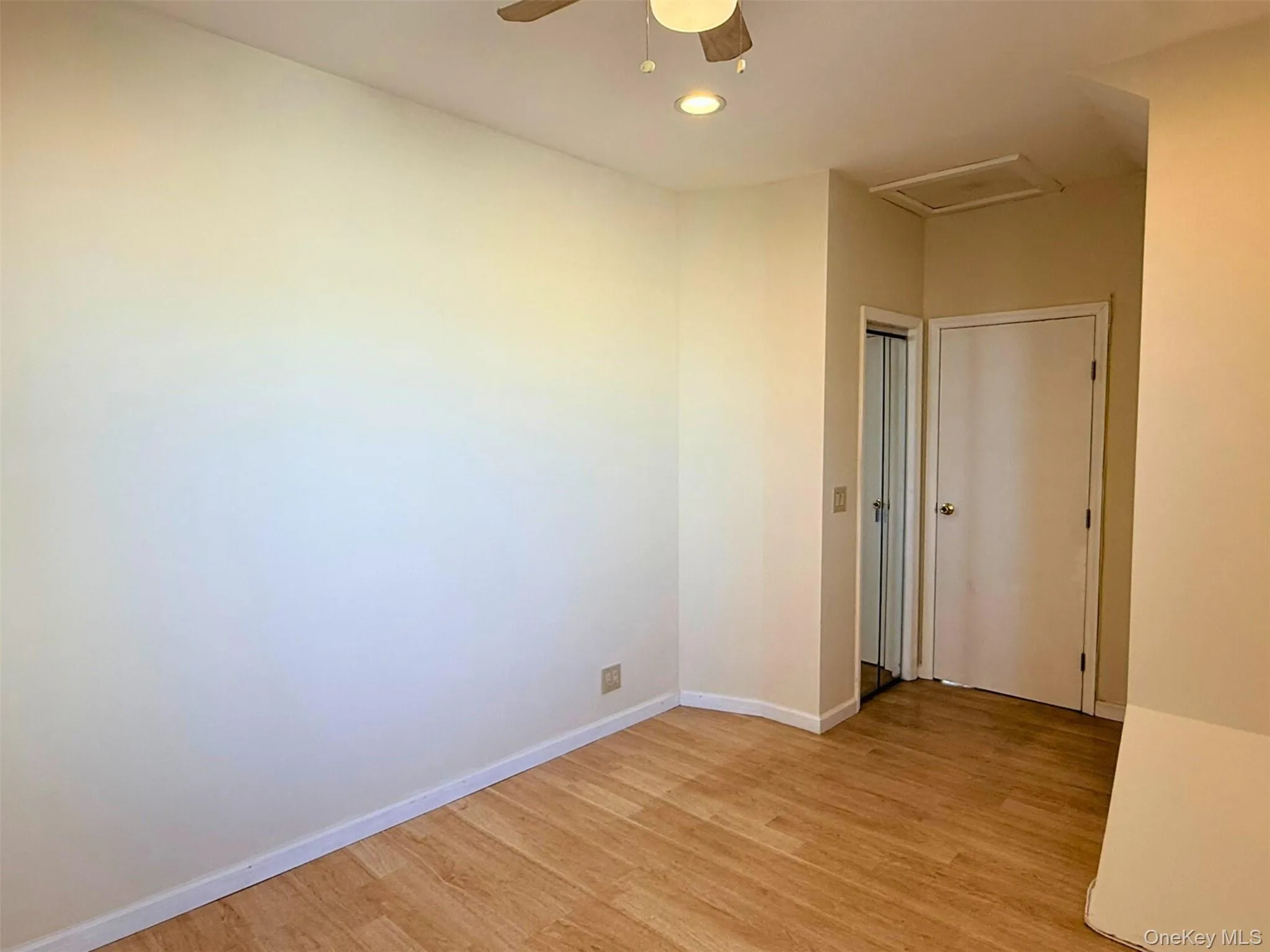 Unfurnished room featuring light wood-style flooring, a ceiling fan, and attic access Unfurnished room featuring light wood-style flooring, a ceiling fan, and attic access