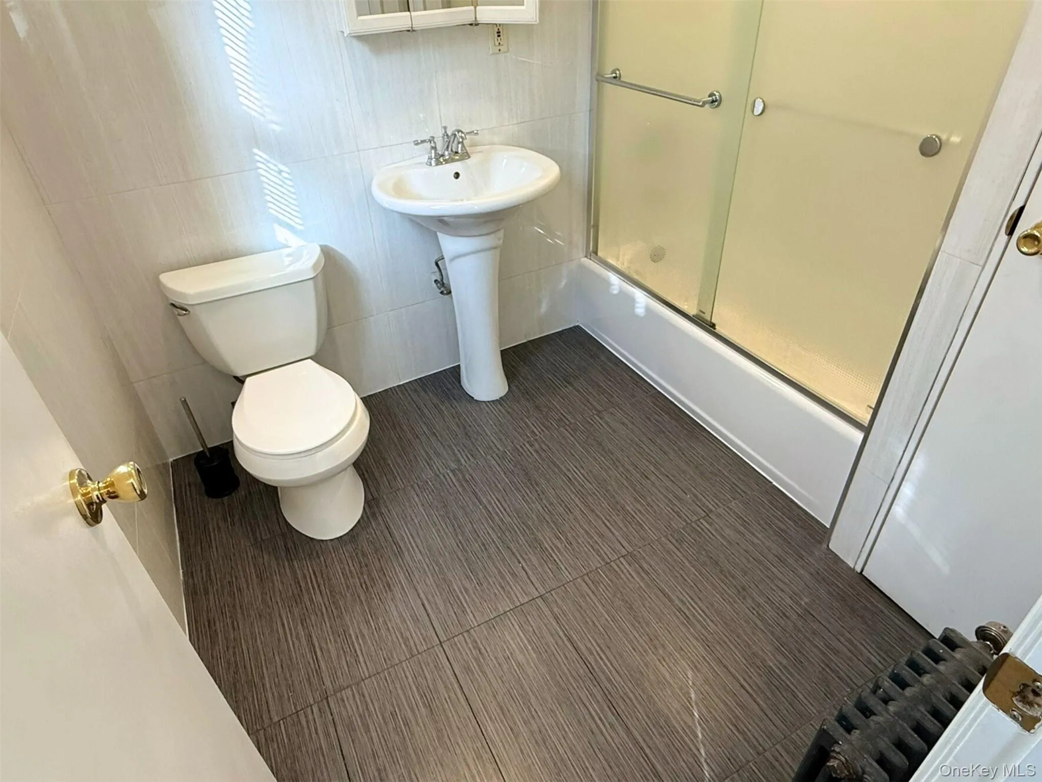 Bathroom featuring enclosed tub / shower combo and tile walls Bathroom featuring enclosed tub / shower combo and tile walls