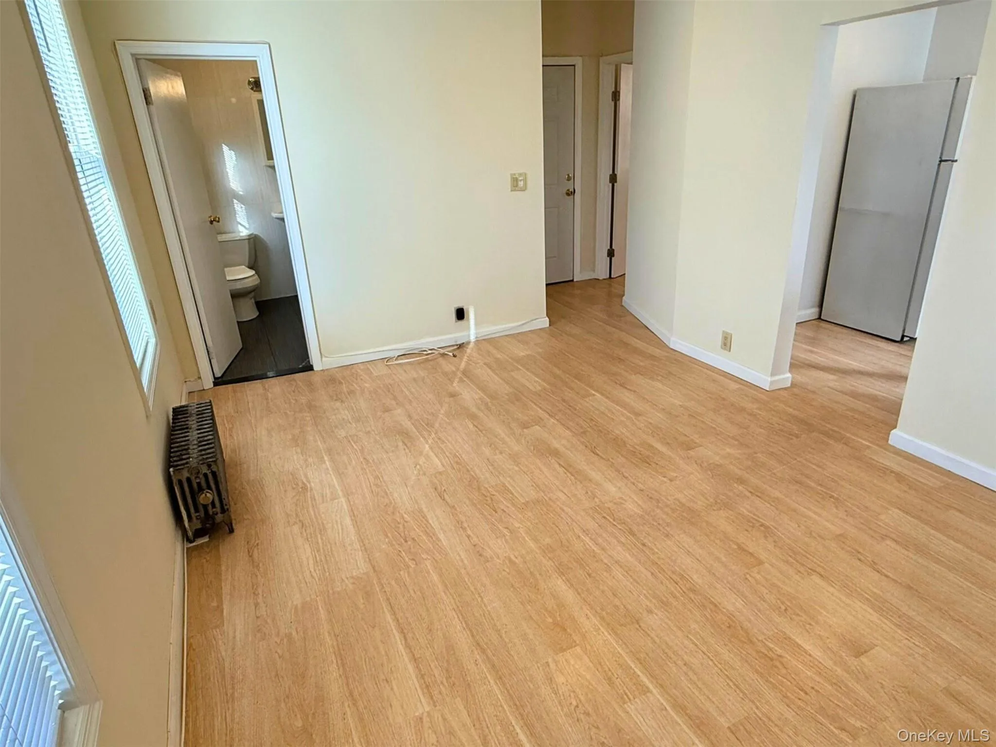 Unfurnished bedroom featuring freestanding refrigerator, light wood finished floors, and connected bathroom Unfurnished bedroom featuring freestanding refrigerator, light wood finished floors, and connected bathroom