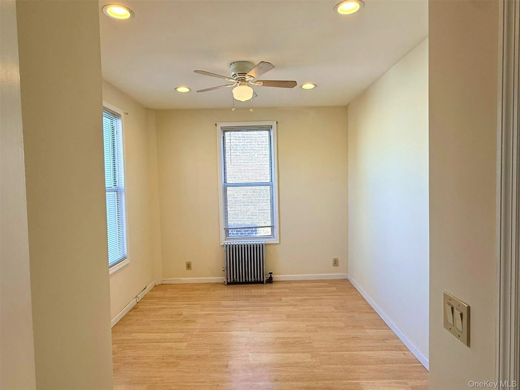 Spare room featuring light wood-style floors, radiator, recessed lighting, and ceiling fan Spare room featuring light wood-style floors, radiator, recessed lighting, and ceiling fan