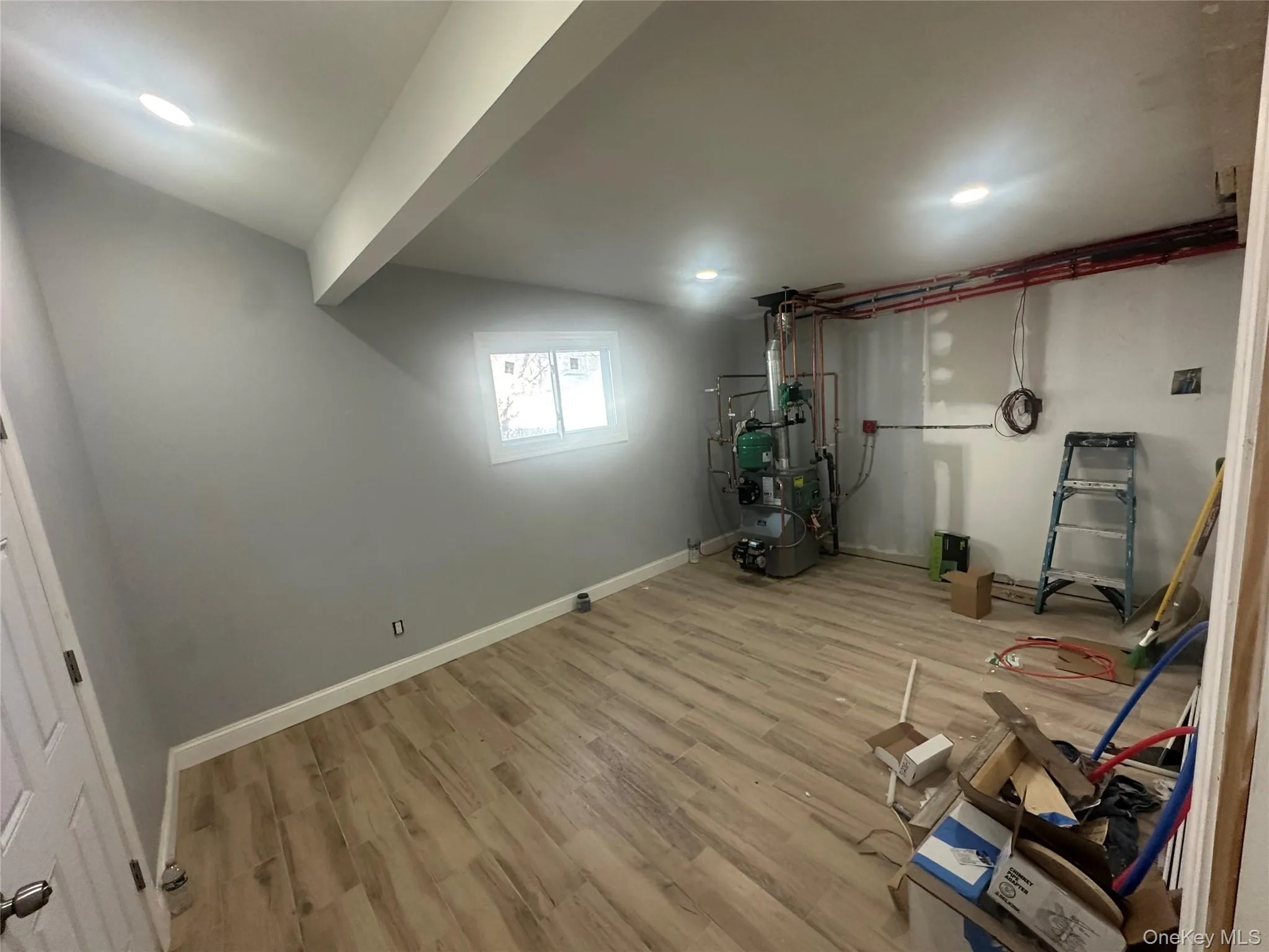 Below grade area with light wood-style flooring and a heating unit Below grade area with light wood-style flooring and a heating unit