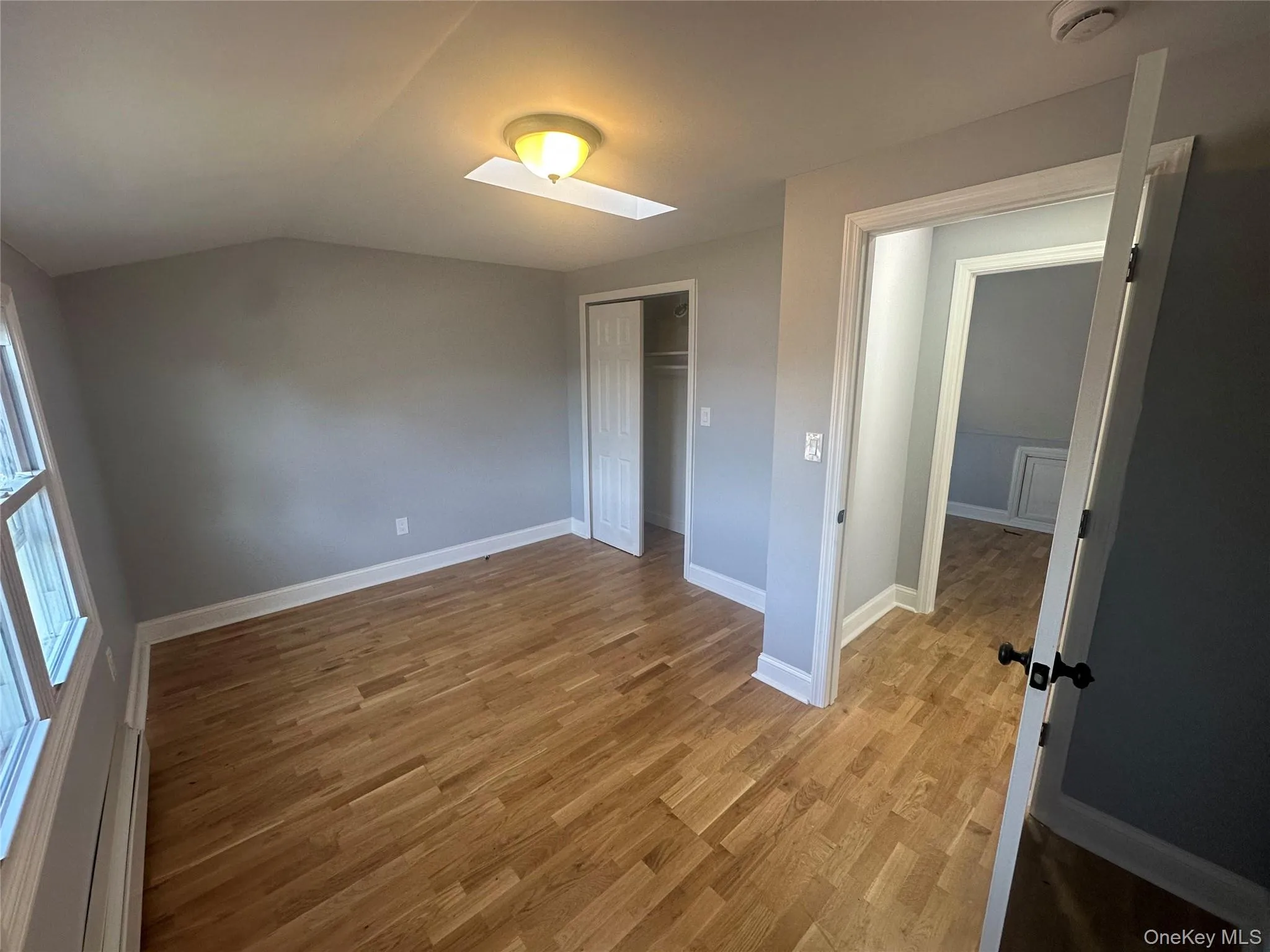 Unfurnished bedroom with light wood-type flooring, a closet, a skylight, and lofted ceiling Unfurnished bedroom with light wood-type flooring, a closet, a skylight, and lofted ceiling