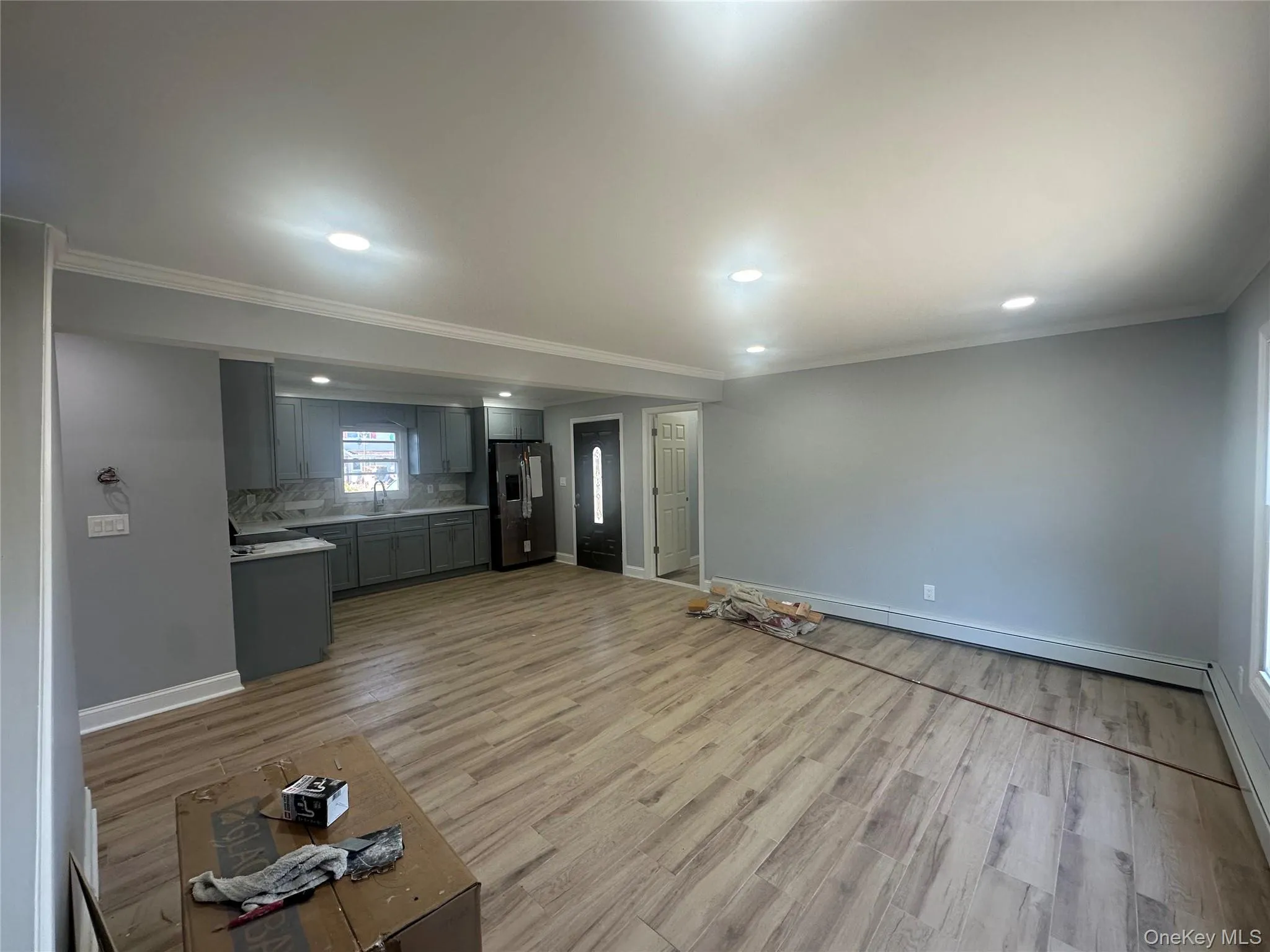 Unfurnished living room with light wood finished floors, ornamental molding, baseboard heating, and recessed lighting Unfurnished living room with light wood finished floors, ornamental molding, baseboard heating, and recessed lighting