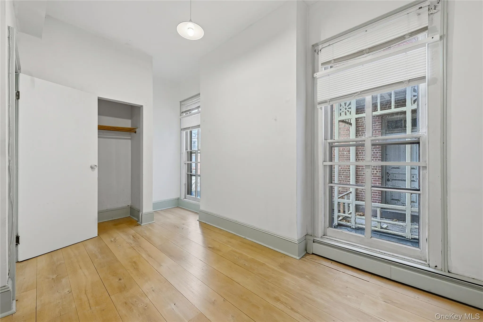 Unfurnished bedroom with baseboard heating, light wood-style flooring, and a closet Unfurnished bedroom with baseboard heating, light wood-style flooring, and a closet