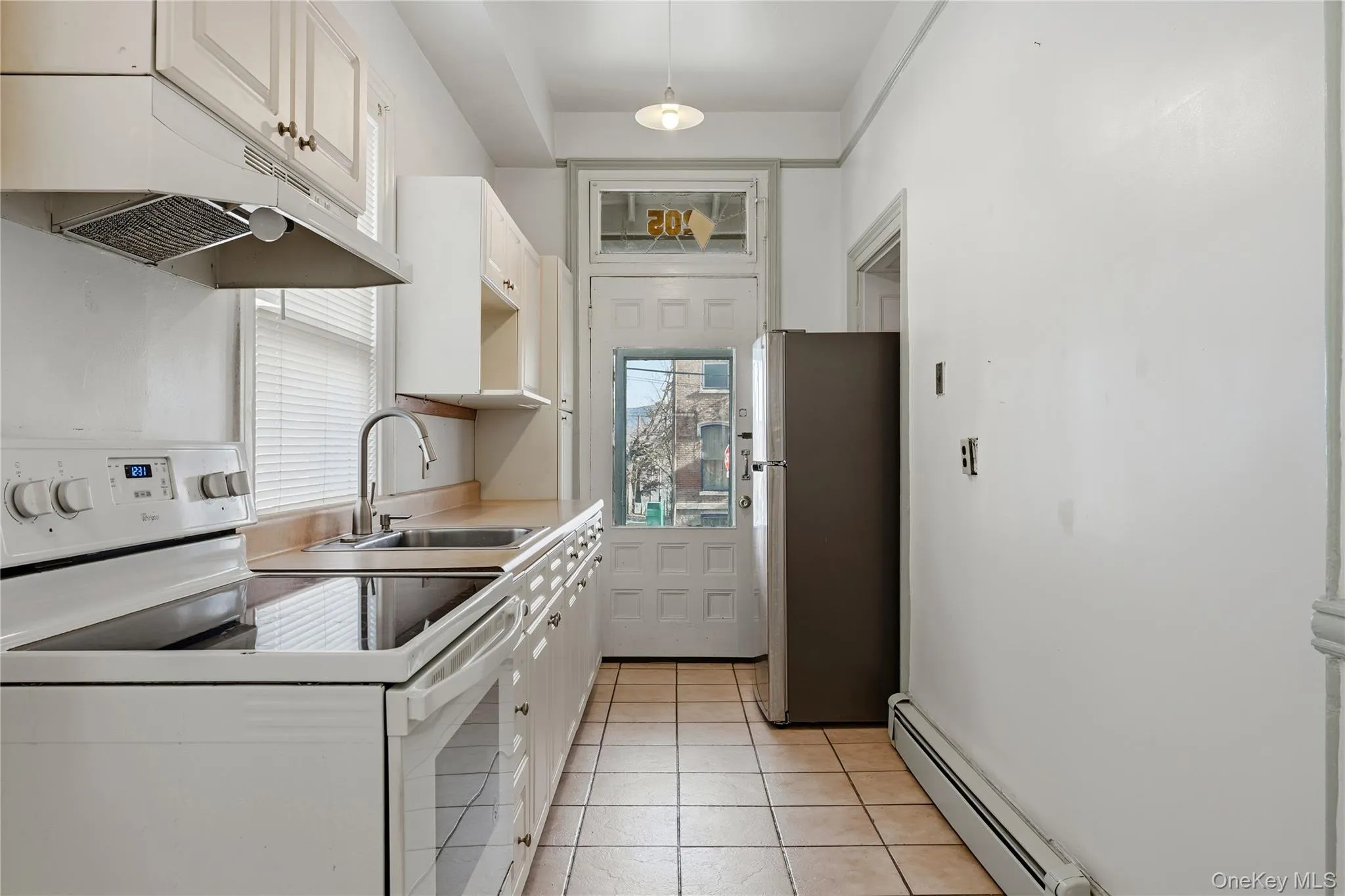 Kitchen featuring white electric range, white cabinets, a baseboard radiator, freestanding refrigerator, and under cabinet range hood Kitchen featuring white electric range, white cabinets, a baseboard radiator, freestanding refrigerator, and under cabinet range hood
