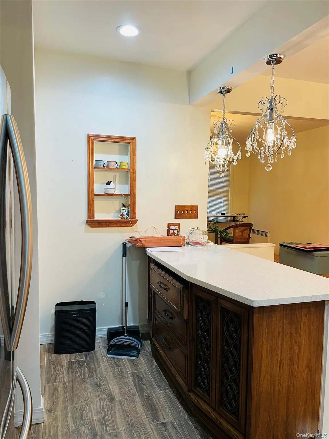 Kitchen featuring a peninsula, freestanding refrigerator, decorative light fixtures, dark wood finished floors, and dark brown cabinetry Kitchen featuring a peninsula, freestanding refrigerator, decorative light fixtures, dark wood finished floors, and dark brown cabinetry