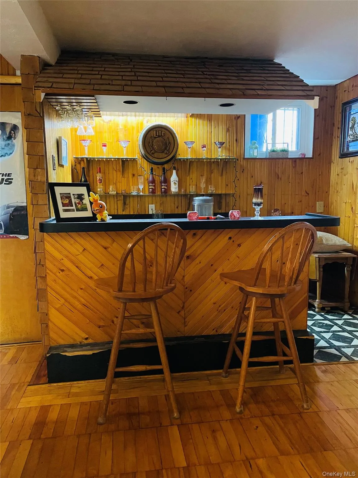 Indoor dry bar with wood walls, wood-type flooring, and dark countertops Indoor dry bar with wood walls, wood-type flooring, and dark countertops