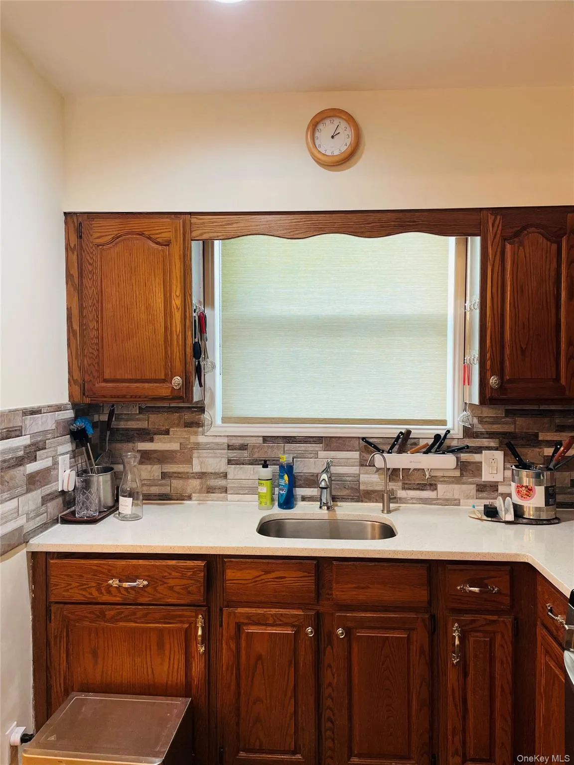 Kitchen with tasteful backsplash, brown cabinetry, and light stone counters Kitchen with tasteful backsplash, brown cabinetry, and light stone counters