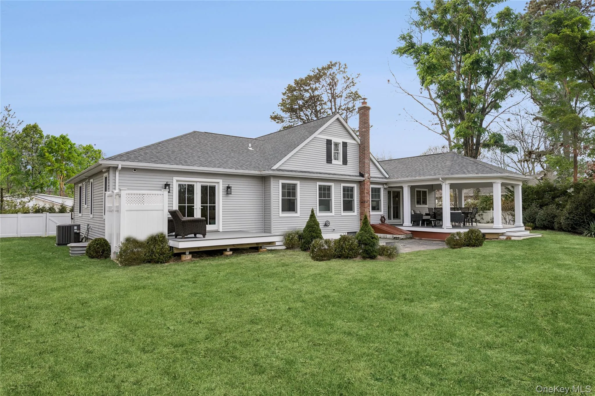 Rear view of house featuring a trex deck, a shingled roof, and a chimney Rear view of house featuring a trex deck, a shingled roof, and a chimney