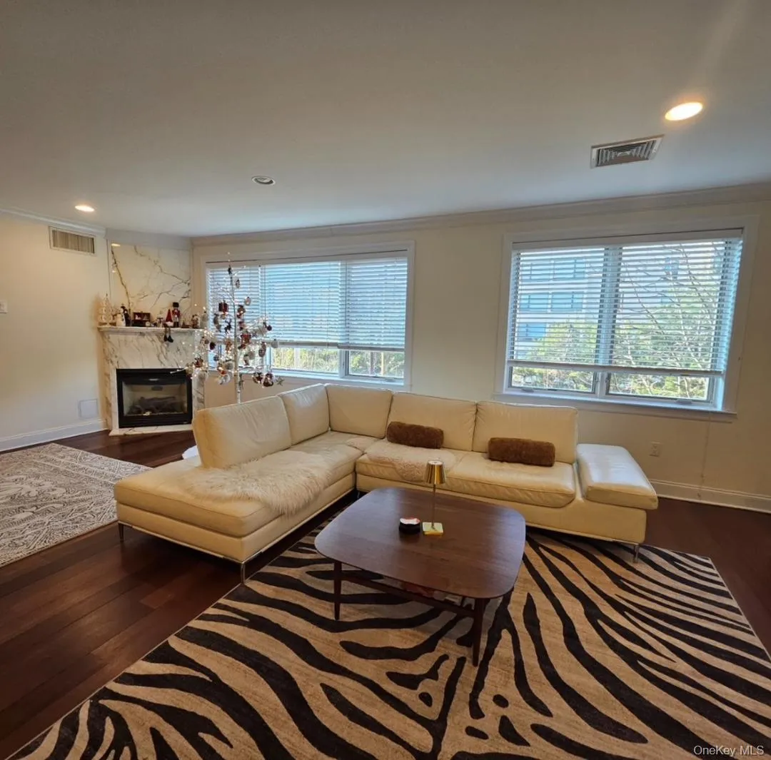 Living room with recessed lighting, dark wood-style floors, crown molding, and a premium fireplace Living room with recessed lighting, dark wood-style floors, crown molding, and a premium fireplace