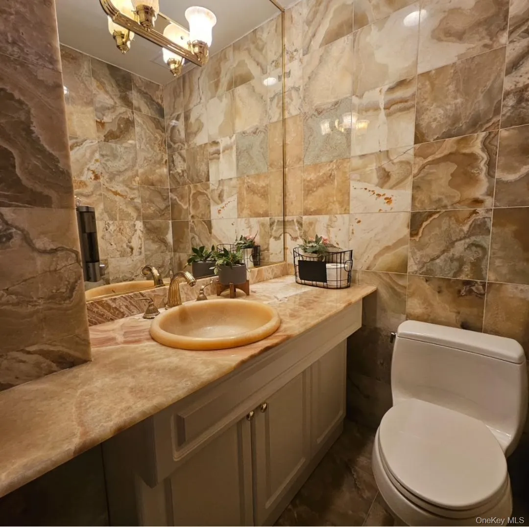 Bathroom featuring tile walls, vanity, and a chandelier Bathroom featuring tile walls, vanity, and a chandelier