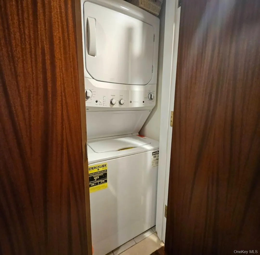 Washroom with stacked washer / dryer and tile patterned flooring Washroom with stacked washer / dryer and tile patterned flooring