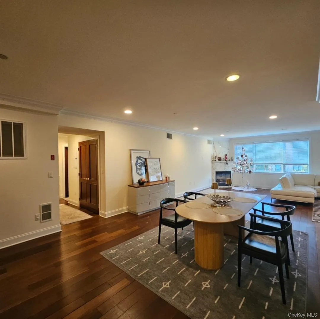 Dining room with ornamental molding, dark wood finished floors, recessed lighting, and a fireplace Dining room with ornamental molding, dark wood finished floors, recessed lighting, and a fireplace