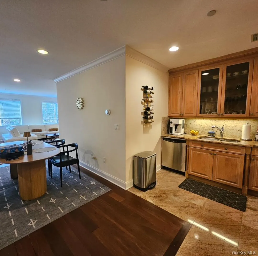 Kitchen with ornamental molding, brown cabinets, dishwasher, recessed lighting, and glass insert cabinets Kitchen with ornamental molding, brown cabinets, dishwasher, recessed lighting, and glass insert cabinets