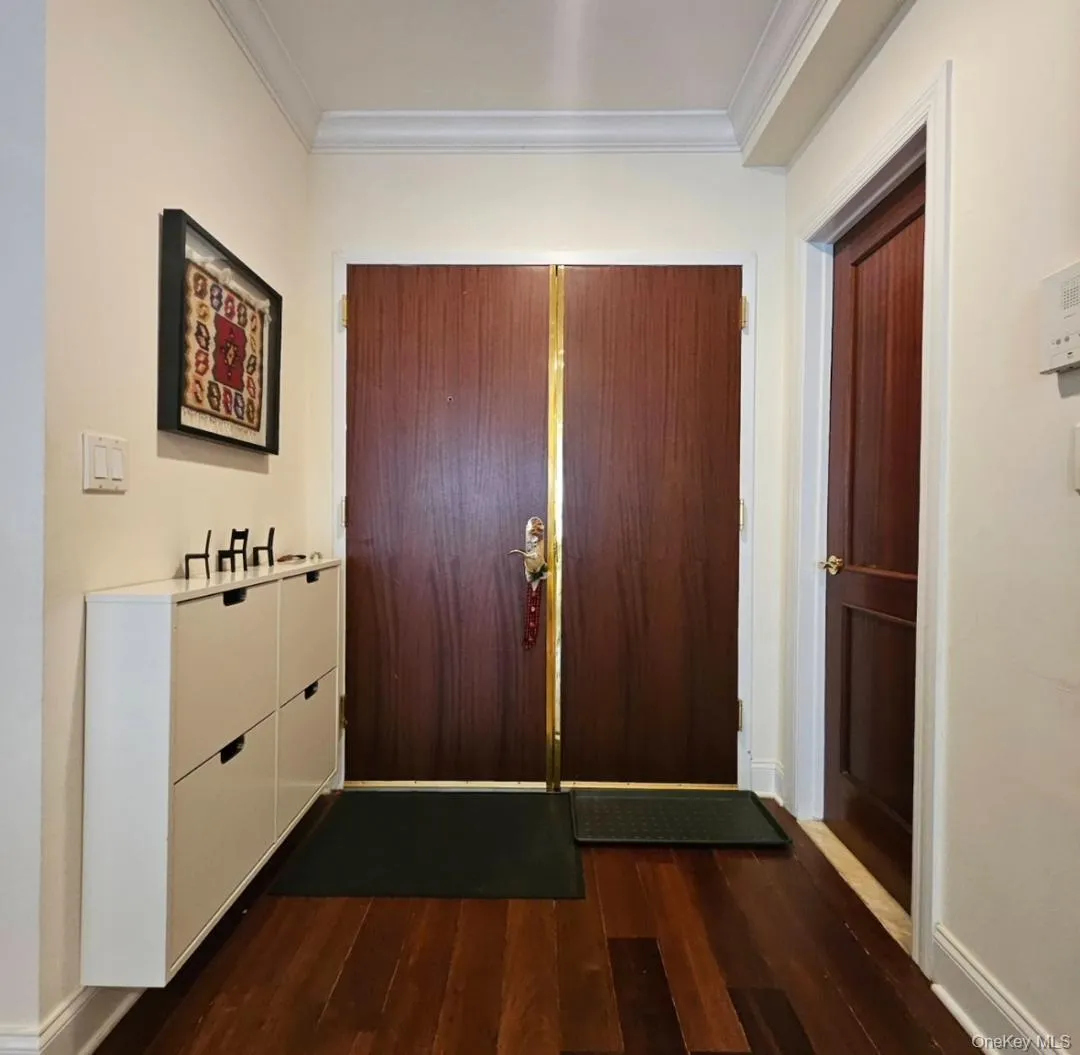 Foyer entrance featuring dark wood-type flooring and crown molding Foyer entrance featuring dark wood-type flooring and crown molding
